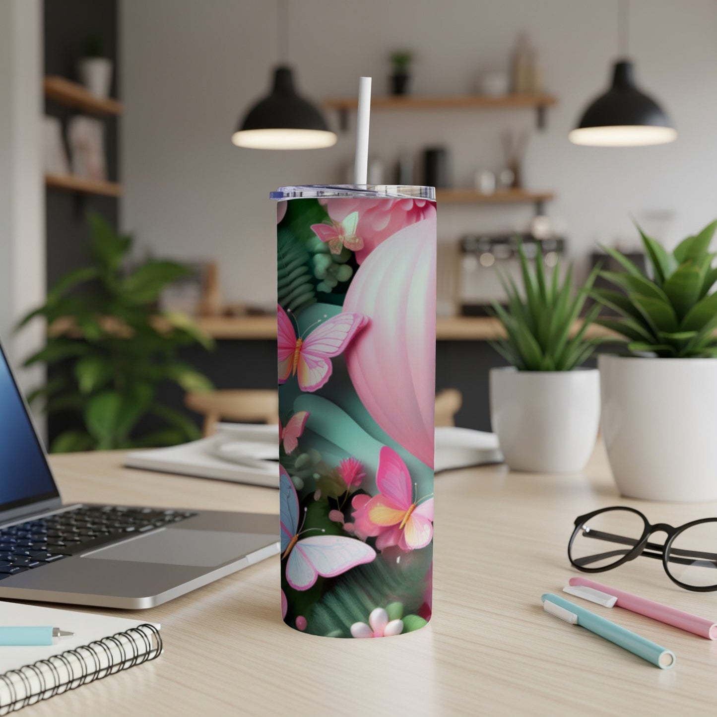 Pink tumbler with butterflies and floral design, on a desk.