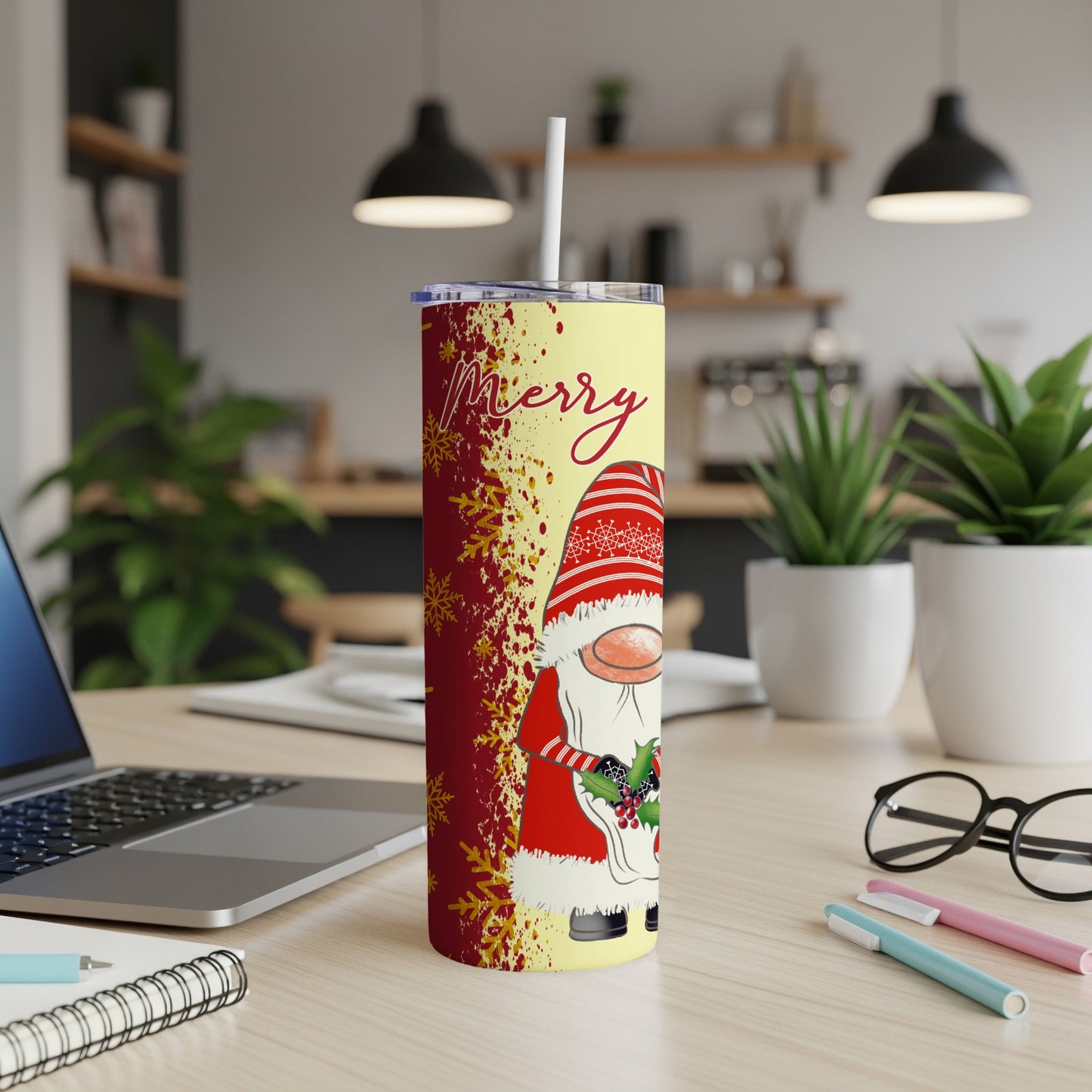 Yellow tumbler with a gnome and "Merry" text, on a desk.