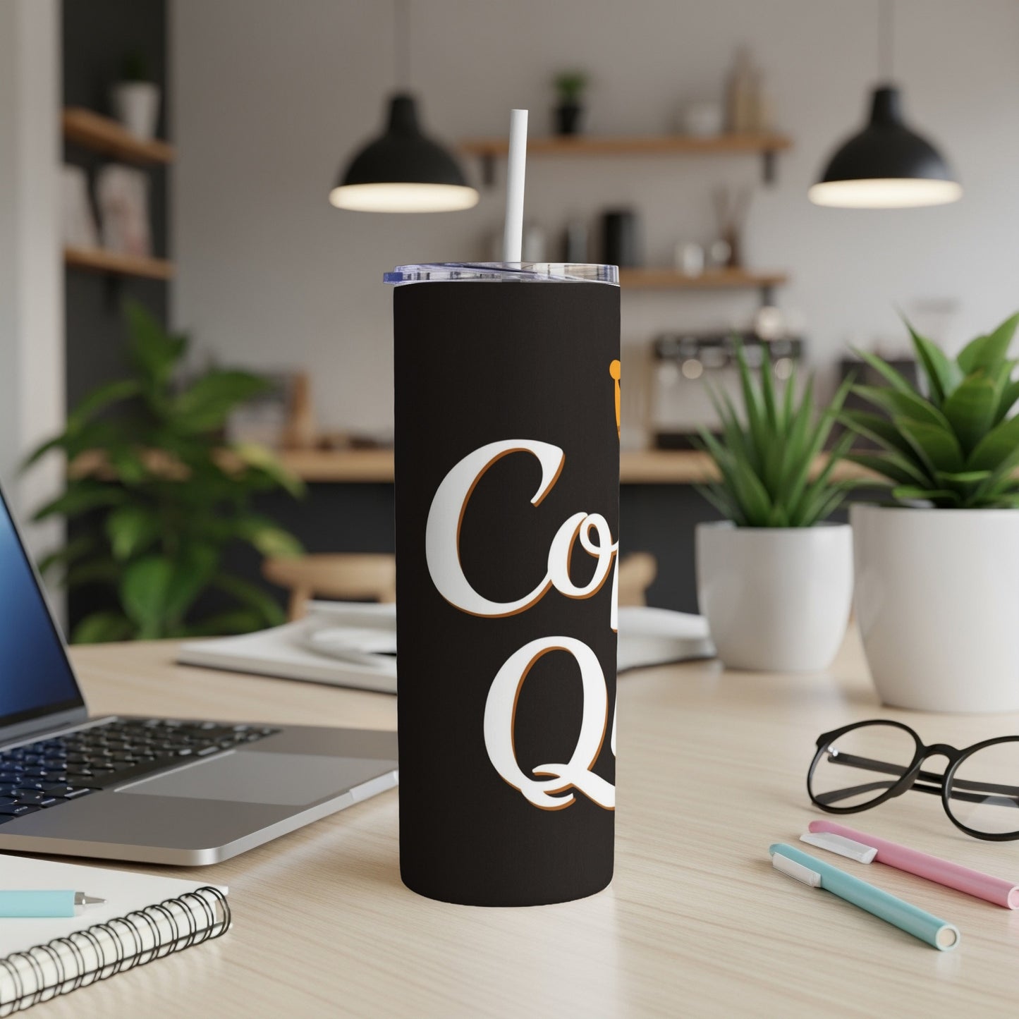 Black tumbler with "Coffee Queen" text and a straw, on a desk.