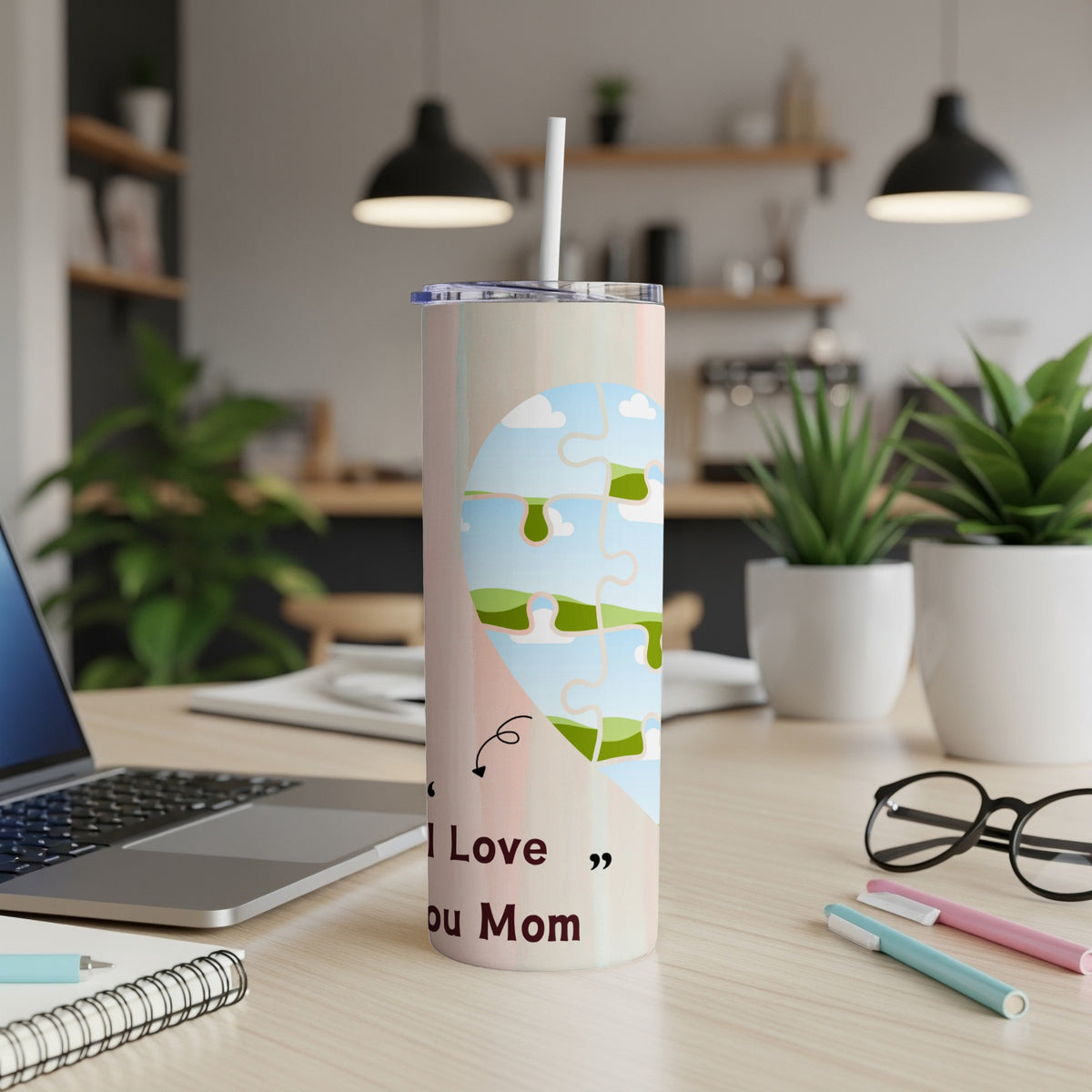 Tumbler with "I Love You Mom" text and puzzle heart design on a desk.