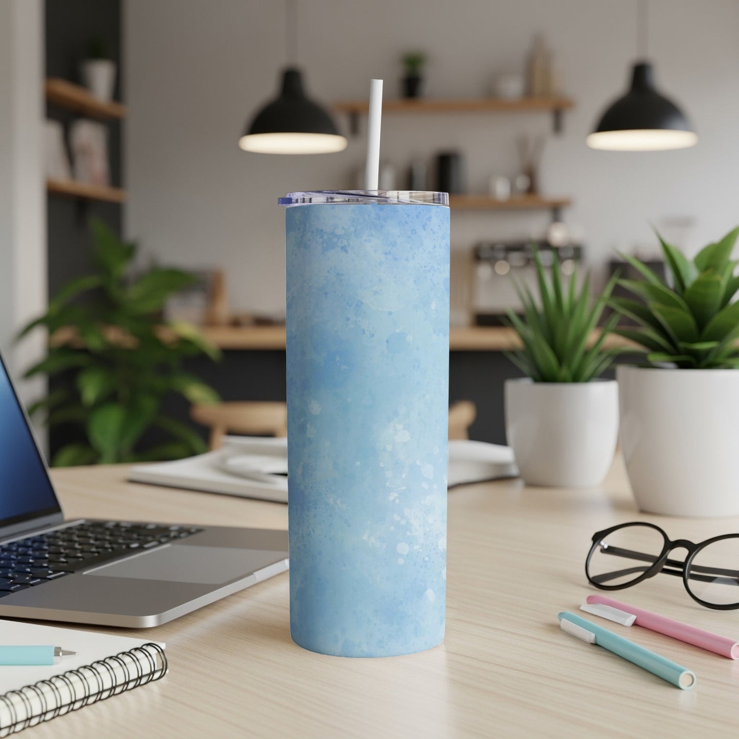 Blue speckled tumbler with straw on a desk with a laptop.