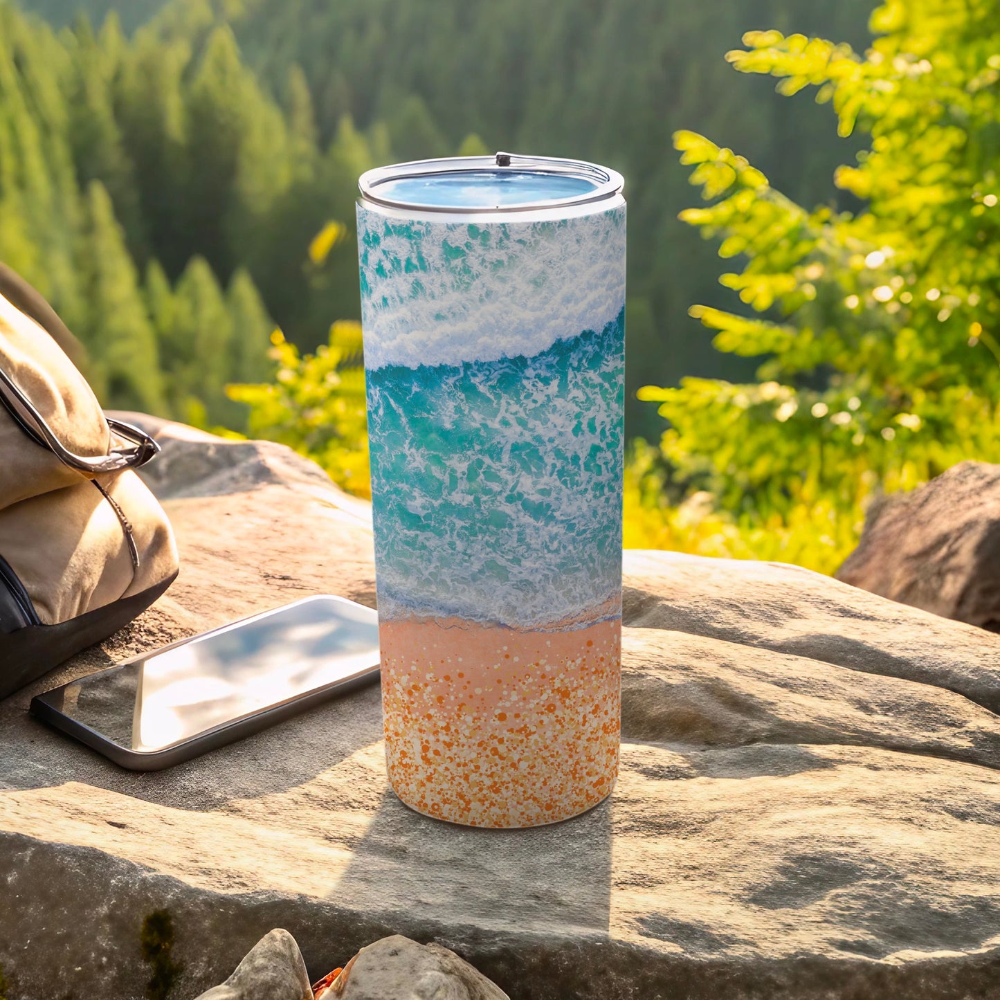 Beach wave and sand pattern on a cylindrical tumbler with a phone and bag.