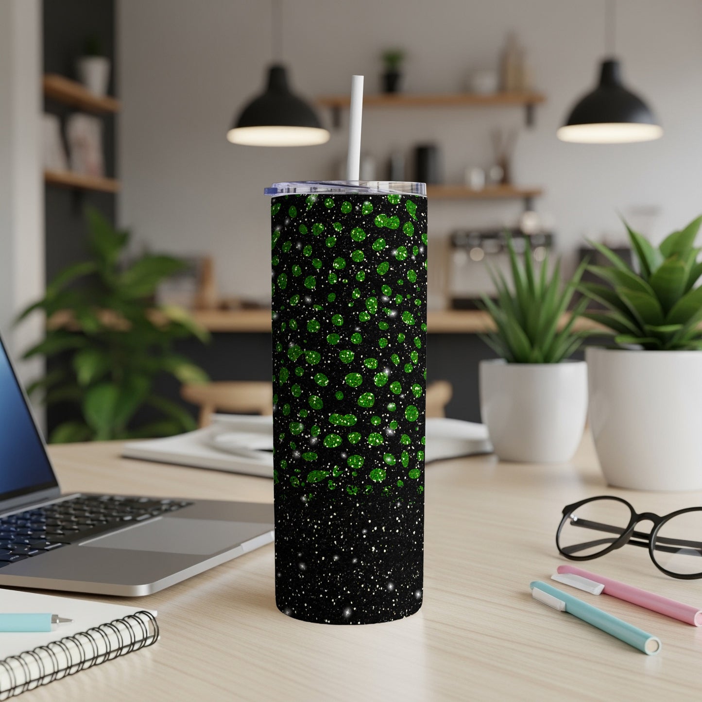 Black tumbler with green glitter gradient and white straw on a desk.