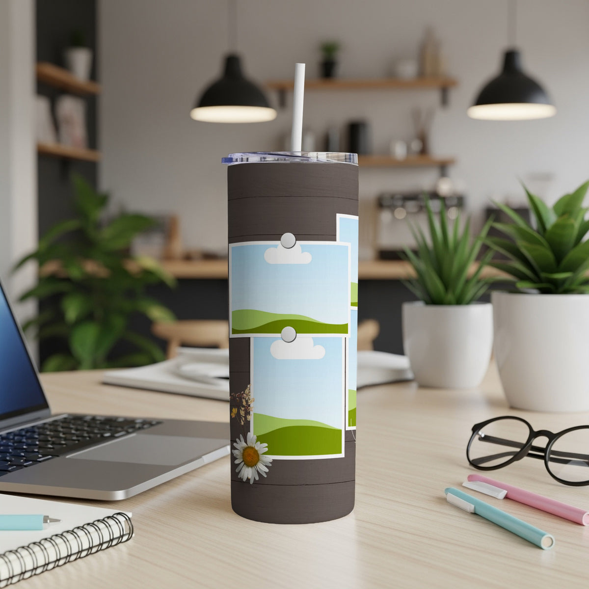 Dark tumbler with a straw and three framed landscape photos, including a daisy.