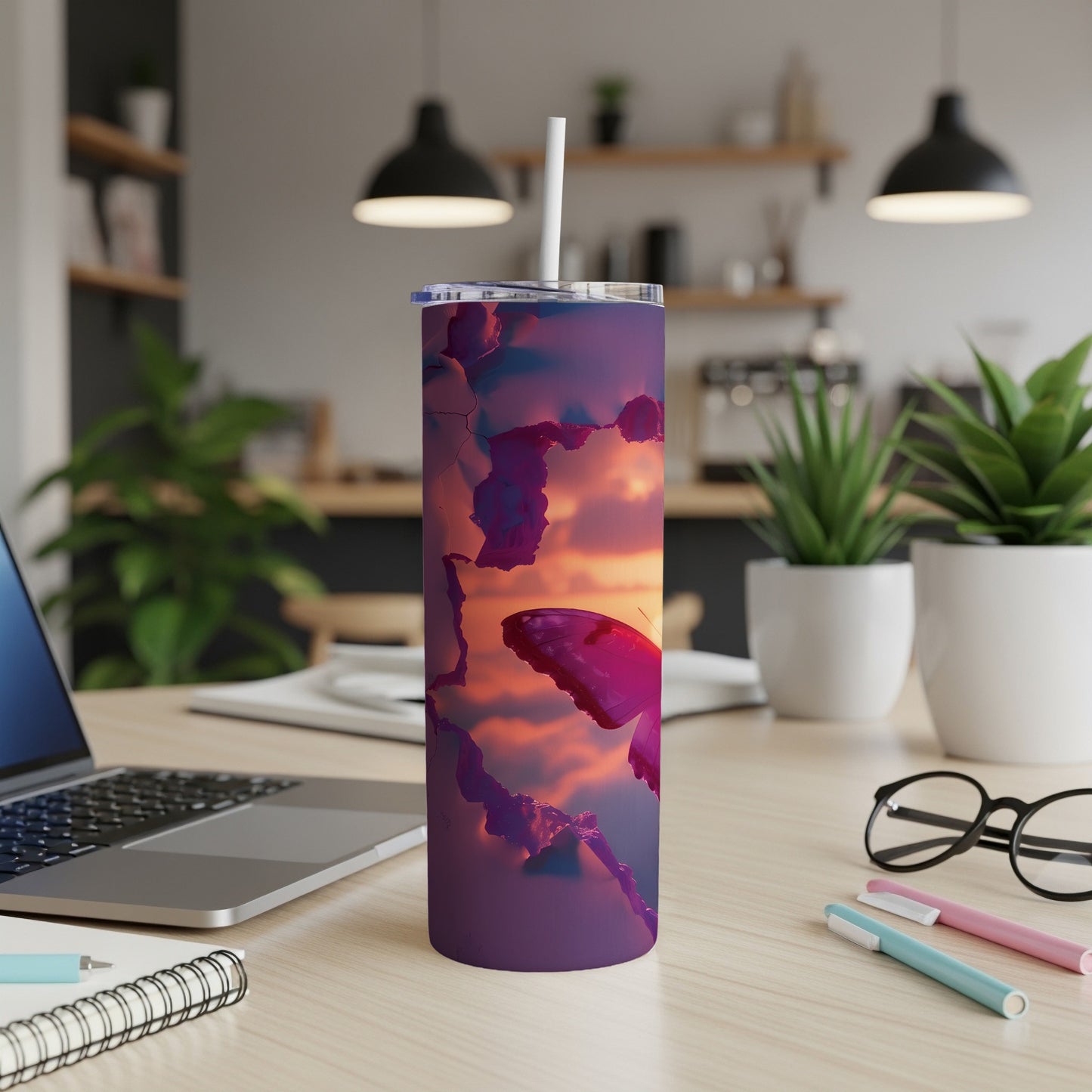 Purple tumbler with butterfly and sunset graphic, on a desk.