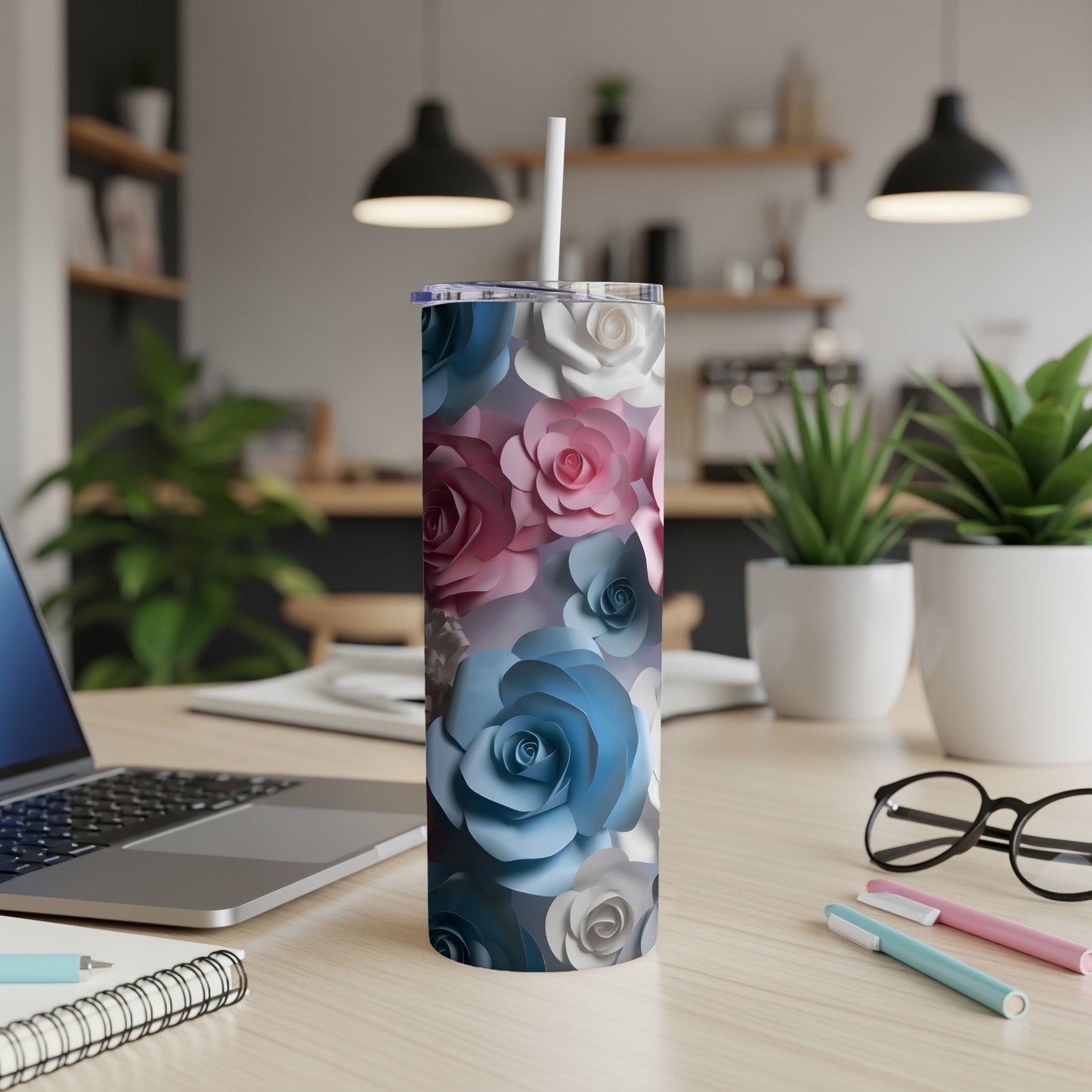 Floral tumbler with blue, pink, and white roses on a desk.