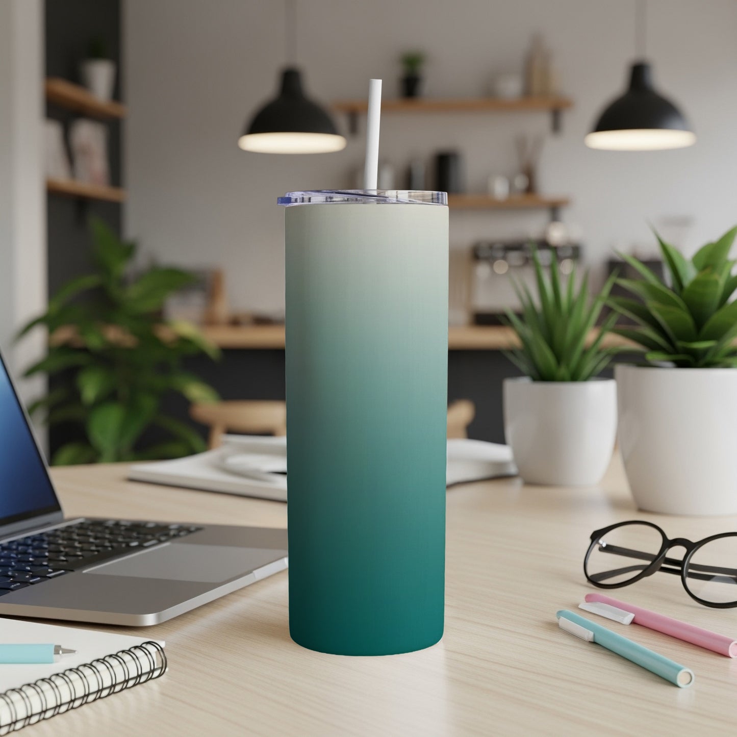 Gradient teal and cream tumbler with straw on a wooden desk.