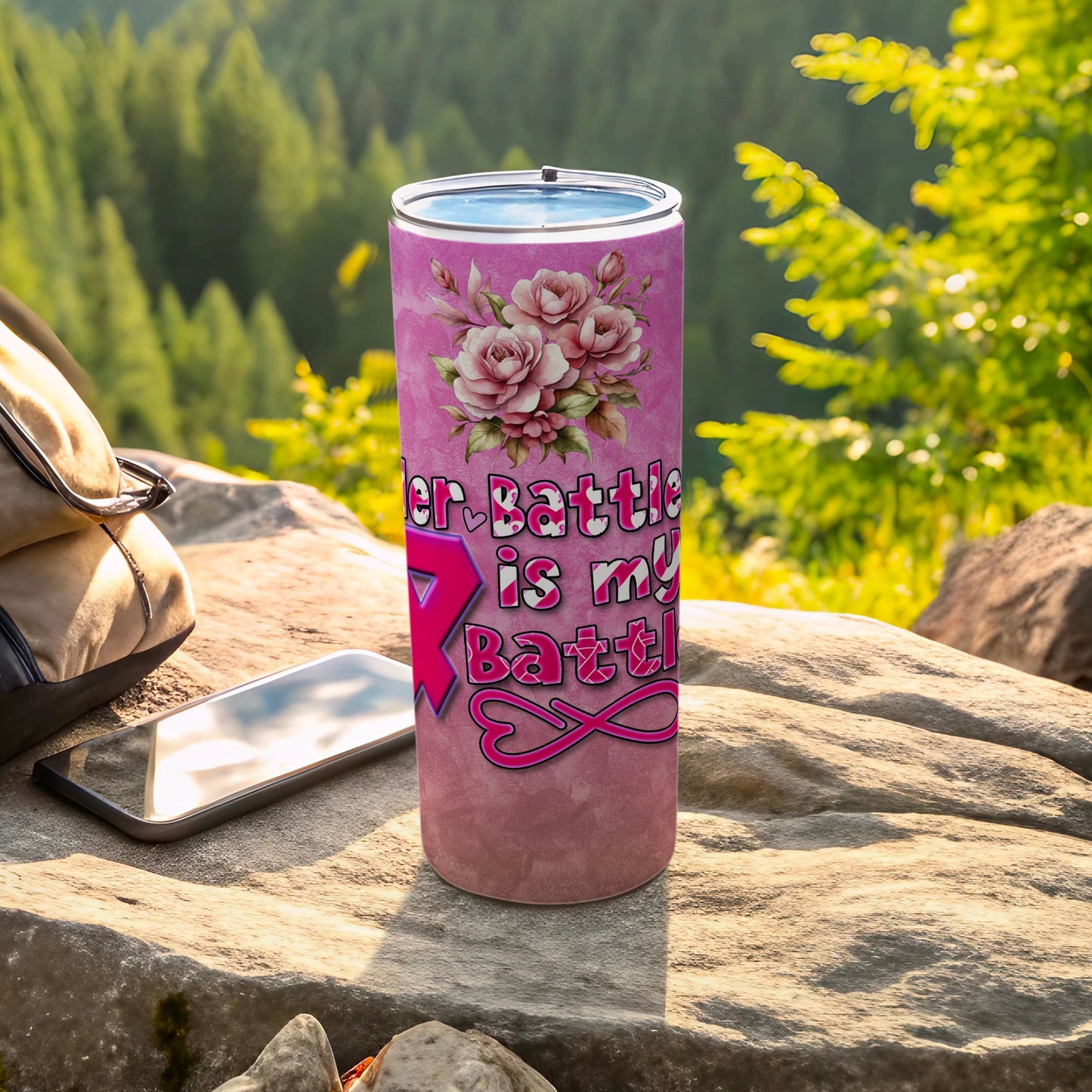 Pink floral tumbler with inspirational text, on a rock outdoors.