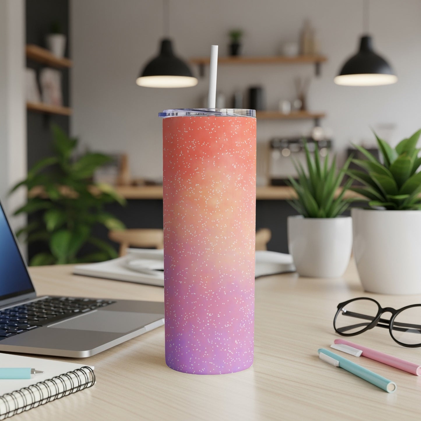 Skinny tumbler with speckled gradient design, straw, and lid on desk.
