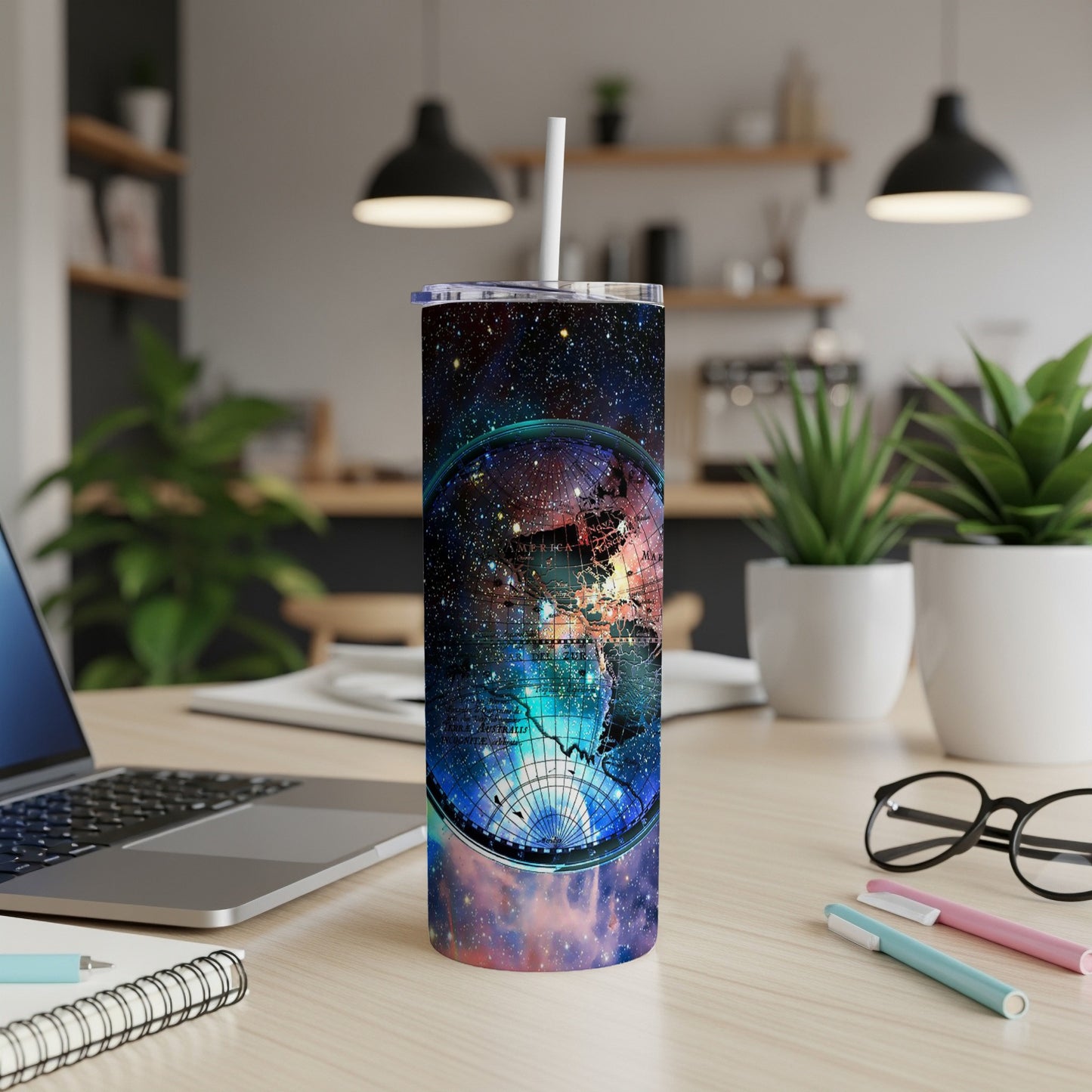 Tumbler with celestial globe design and starry background beside a laptop.