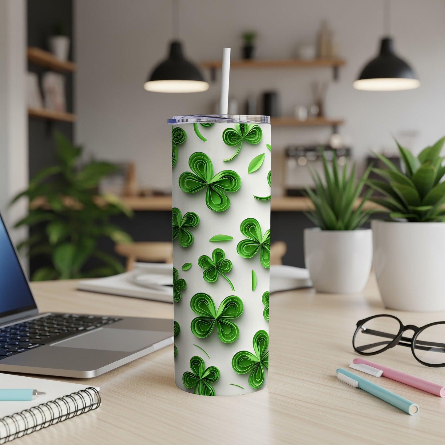 Green shamrock pattern on a white tumbler with a straw on a desk.