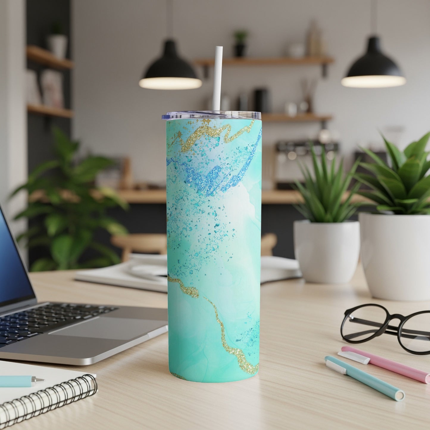 Teal and gold marble tumbler with straw on desk.