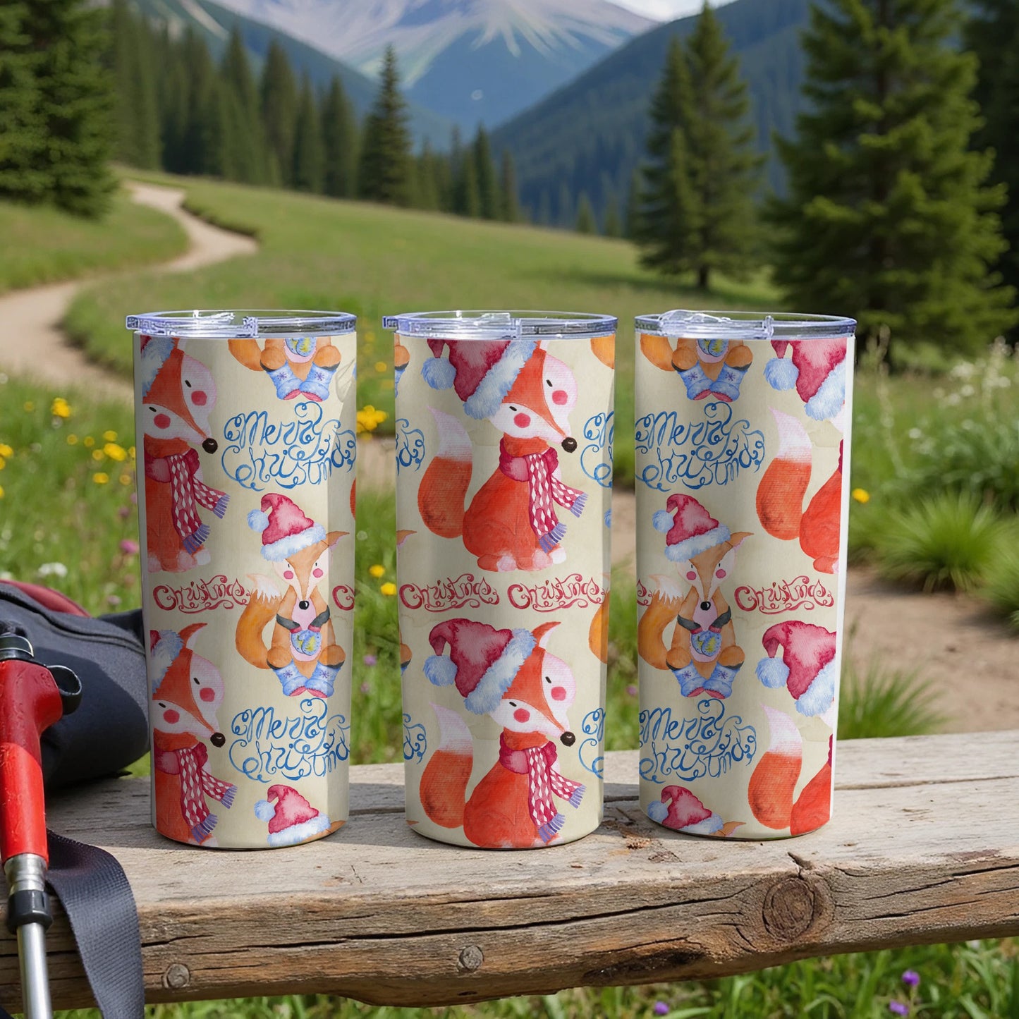 Three tumblers with festive foxes in Santa hats and scarves on a wooden table.