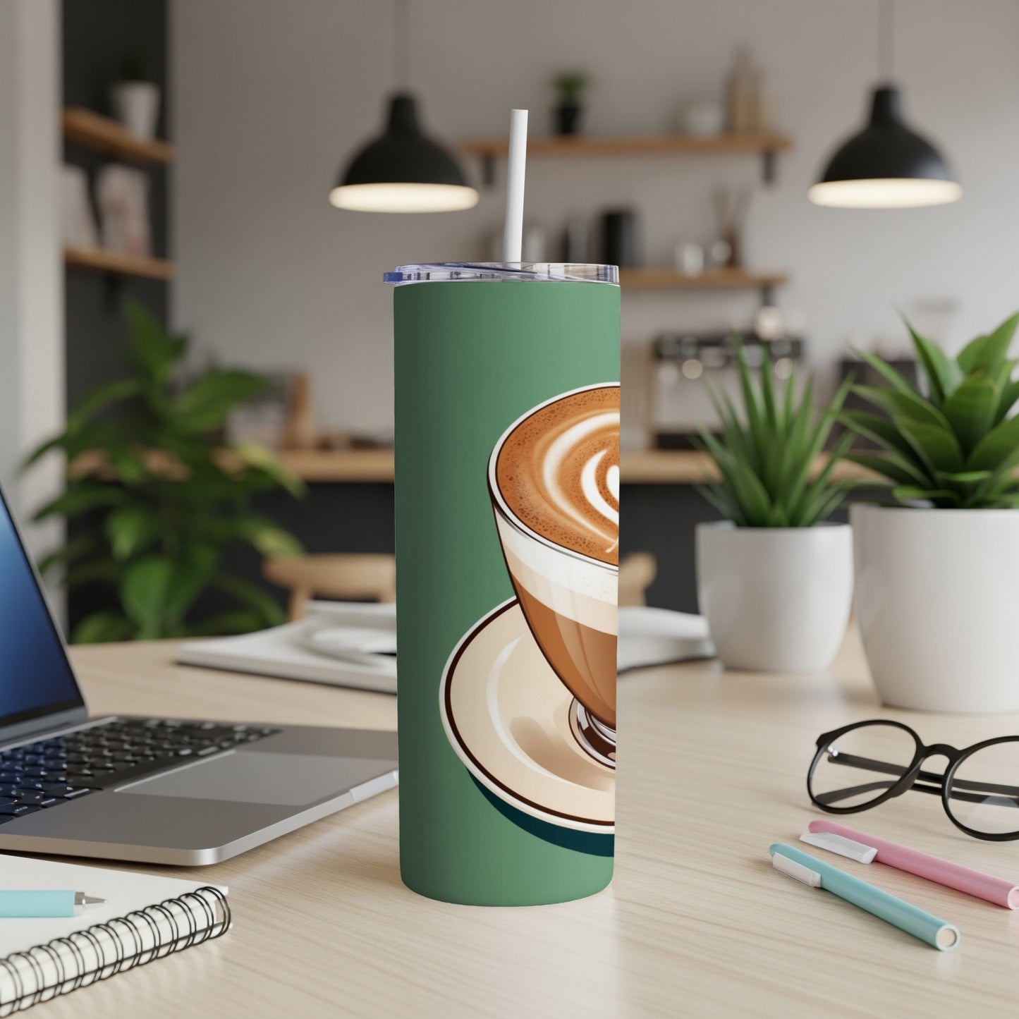 Green tumbler with latte art coffee cup design, on a desk.