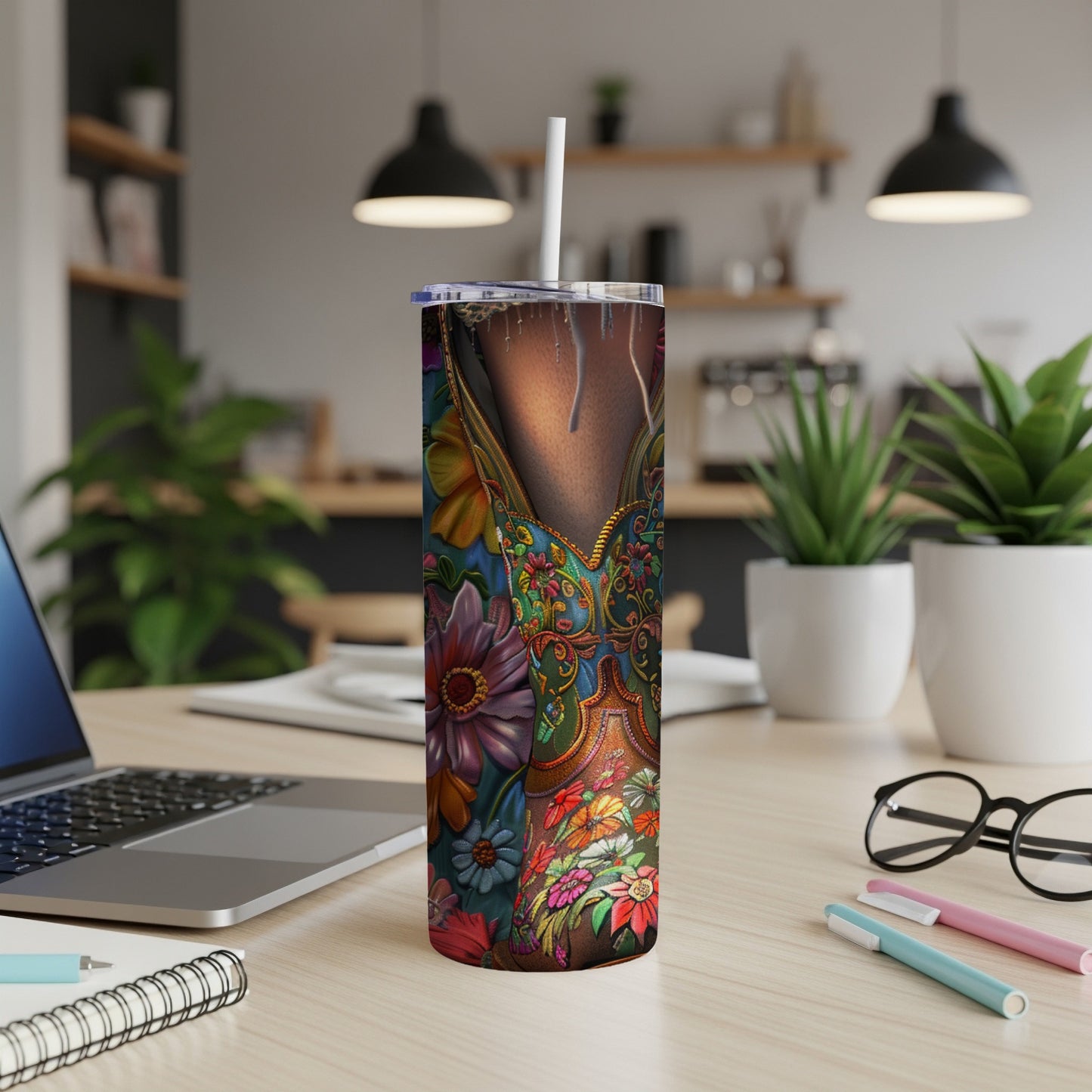 Floral patterned tumbler with a straw on a desk next to a laptop.