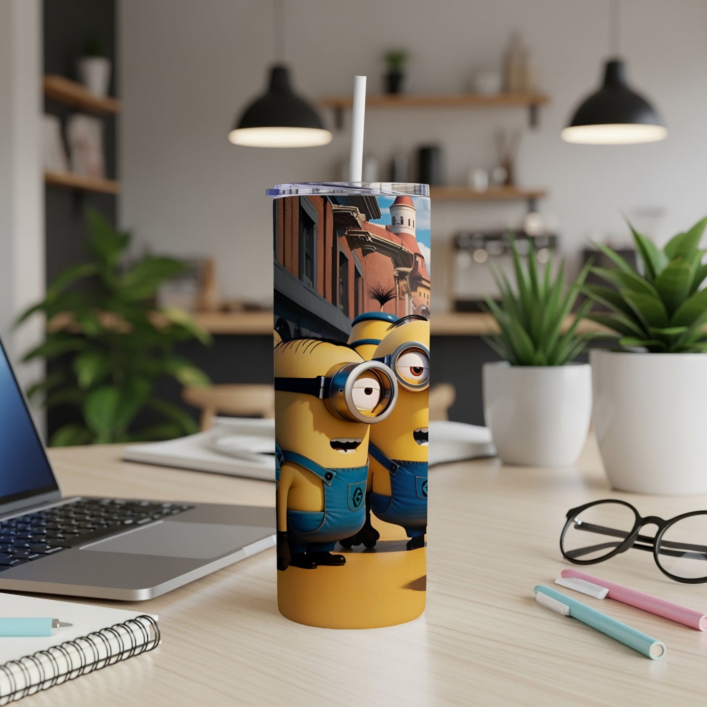 Two Minion characters in blue overalls with a straw on a desk.