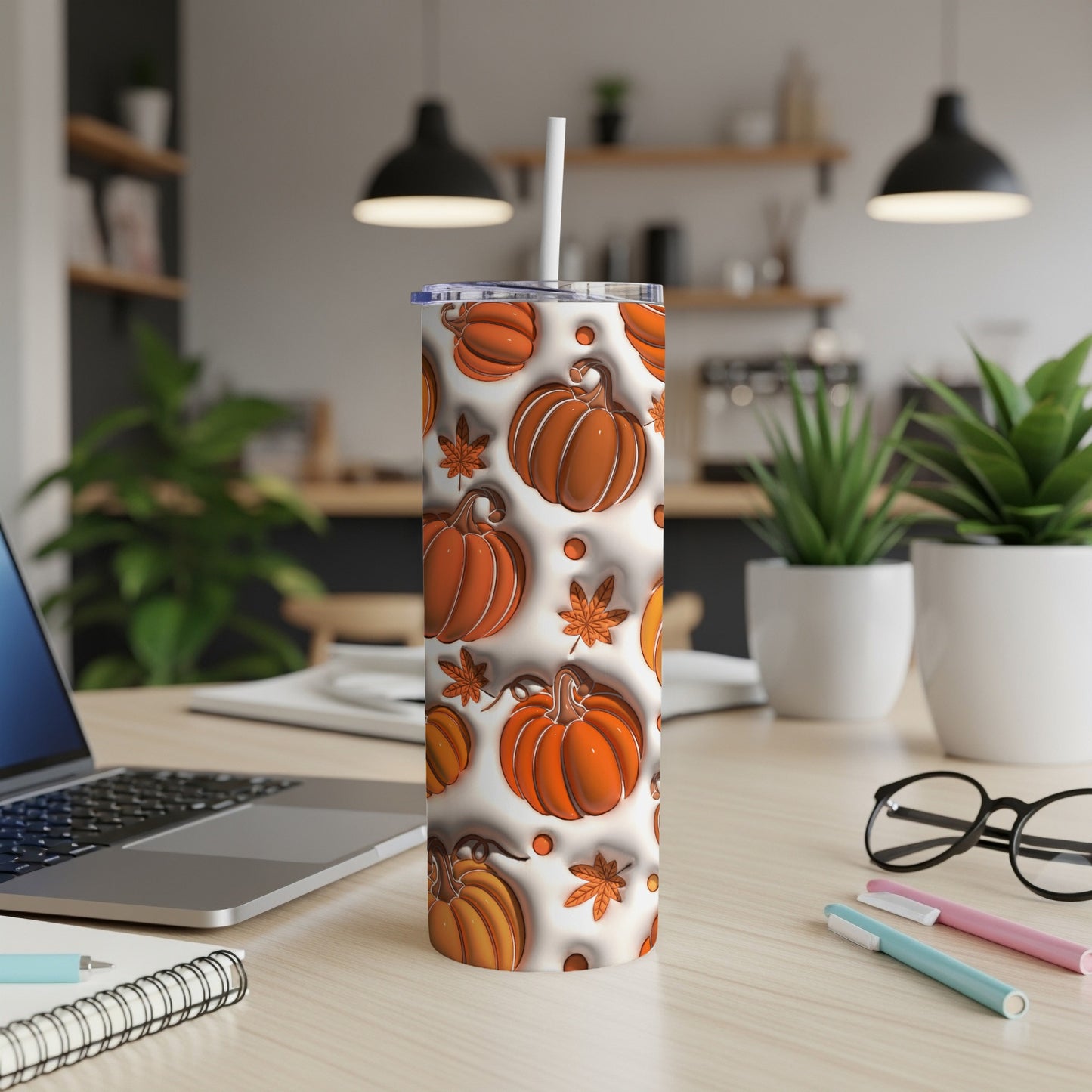 White tumbler with pumpkin and leaf pattern, on desk with laptop.