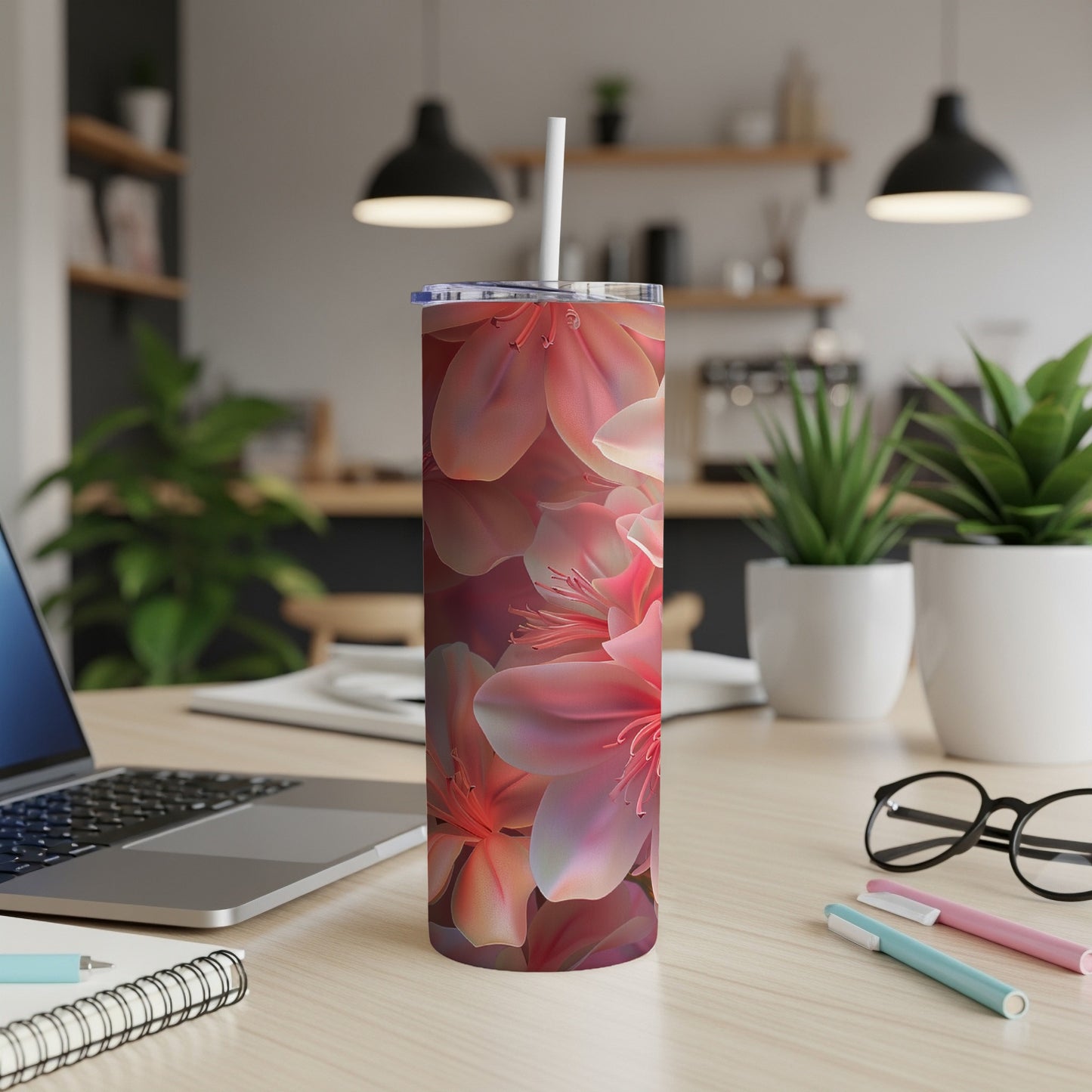 Floral print tumbler with straw on a wooden desk.