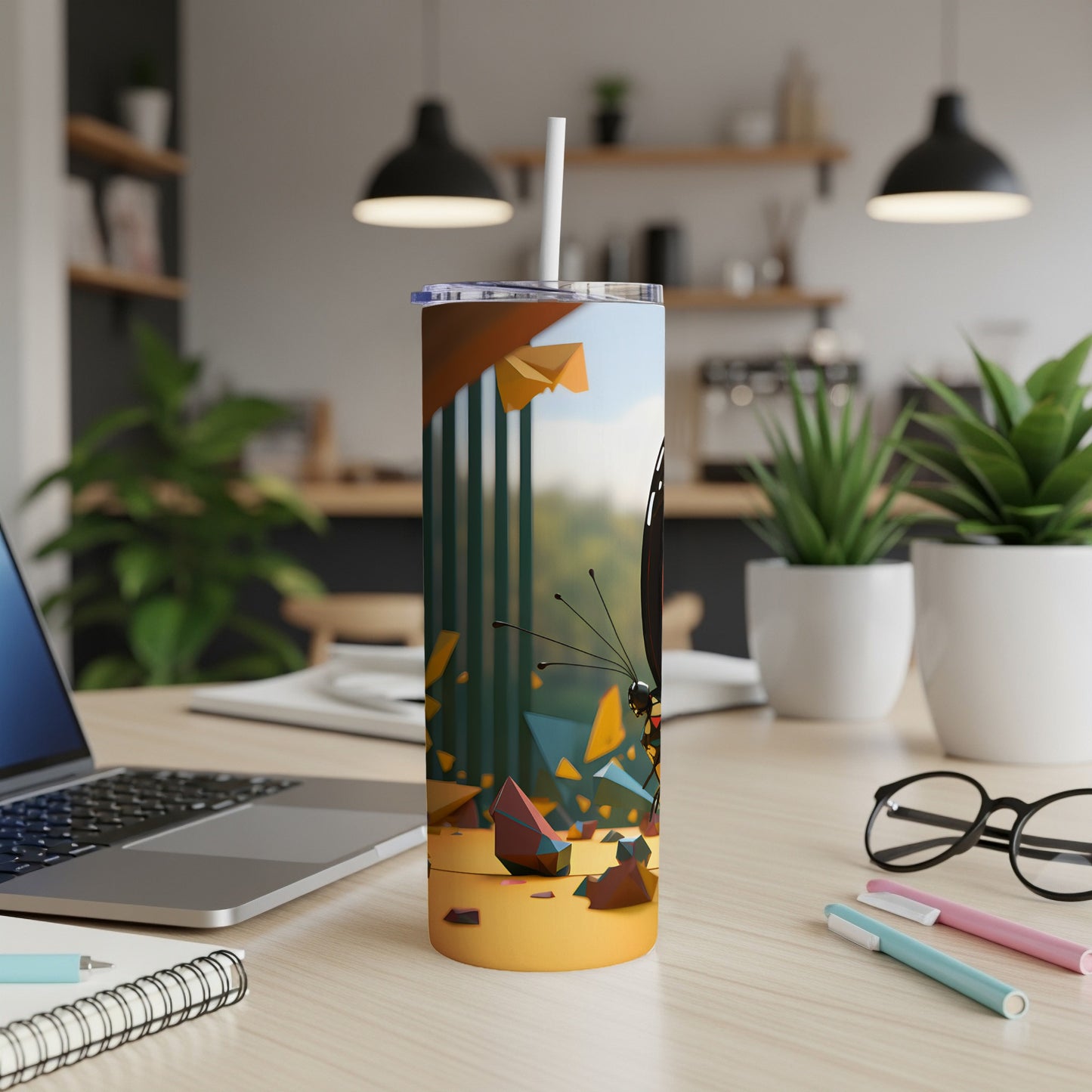 Stainless steel tumbler with butterfly pattern on a desk.