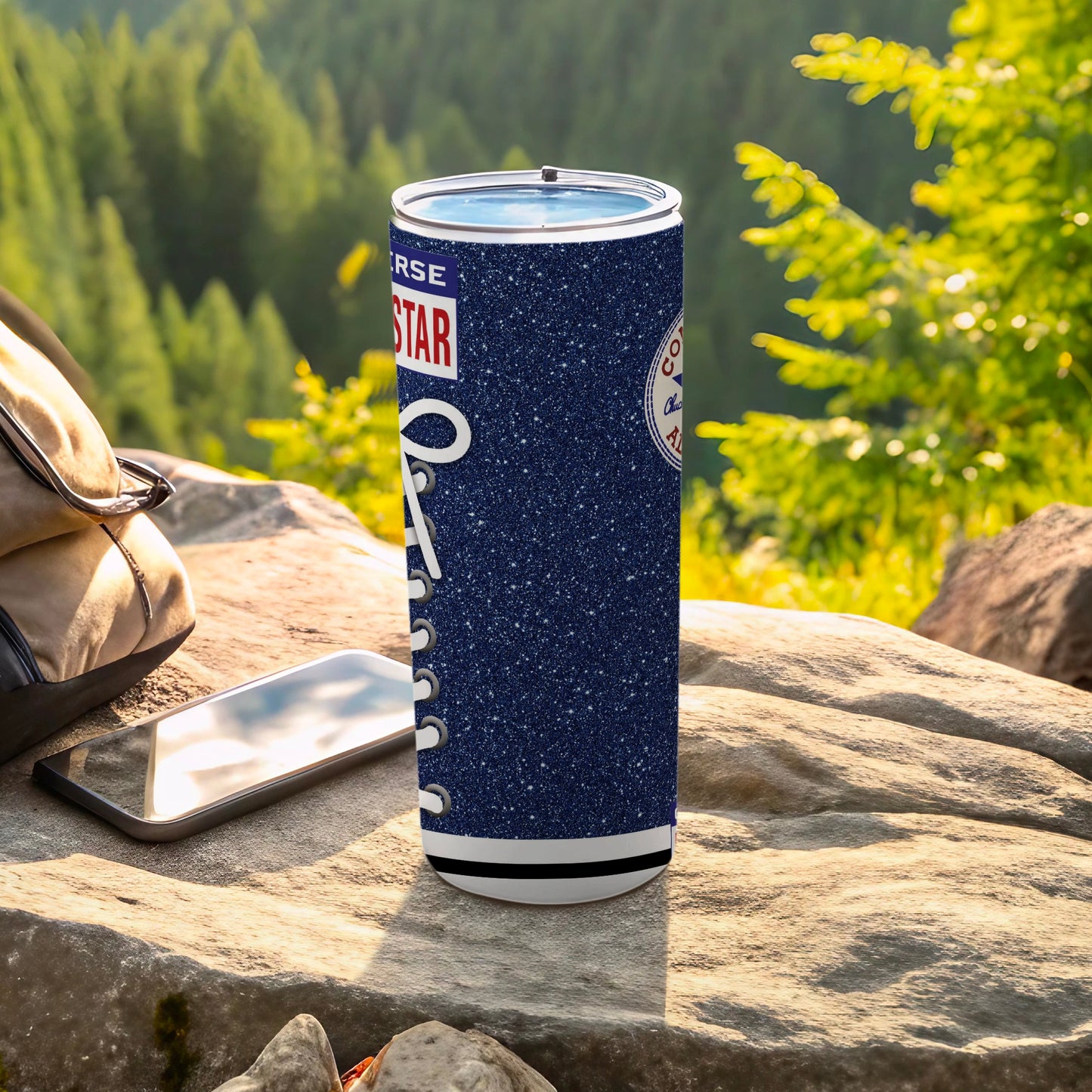 Converse Star logo on sparkly blue tumbler with white laces, beside phone.