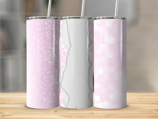 Three pink glitter and torn paper patterned tumblers with straws on a wooden surface.