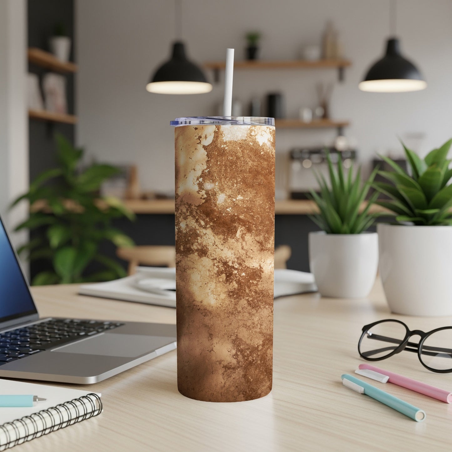 Brown and beige marbled tumbler with straw on desk.
