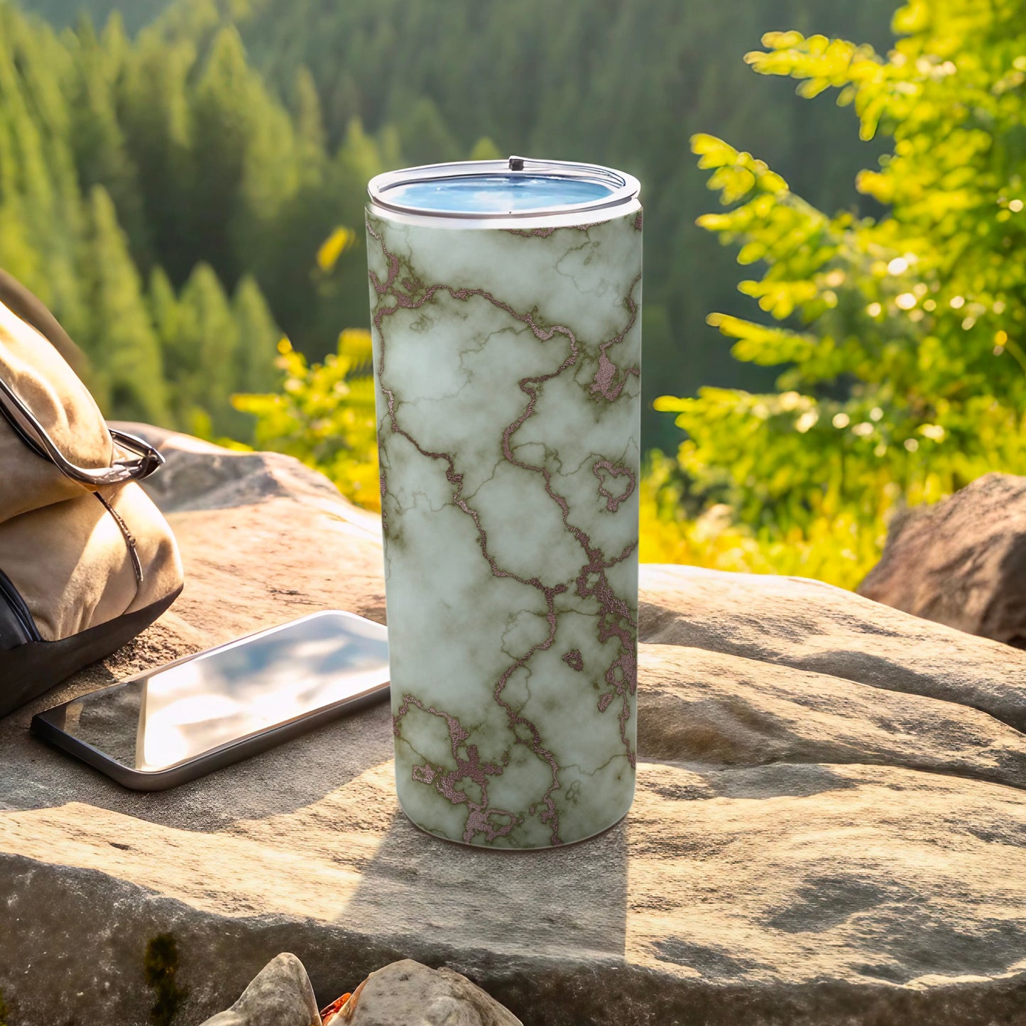 Marble patterned tumbler with rose gold veins on a rocky outdoor surface.