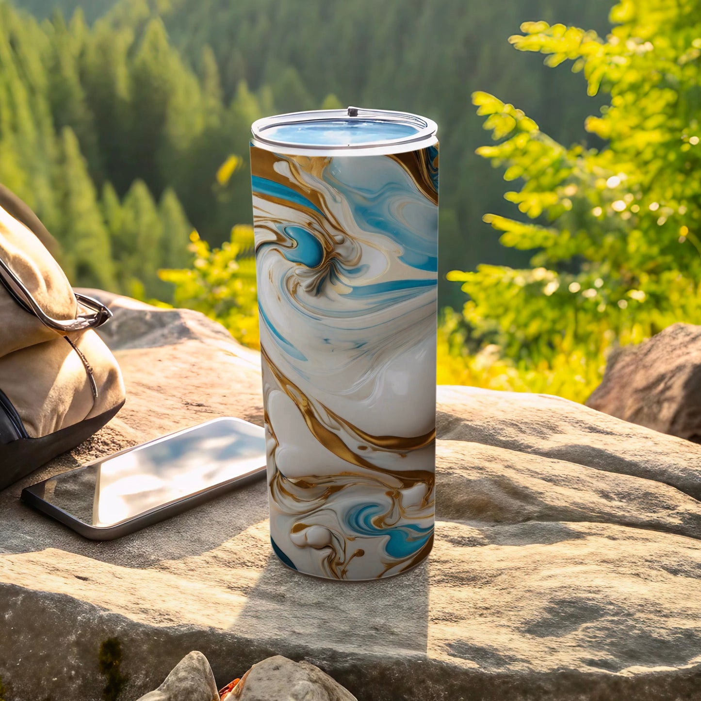 Tall tumbler with blue, gold, and white marbled design on outdoor rock.