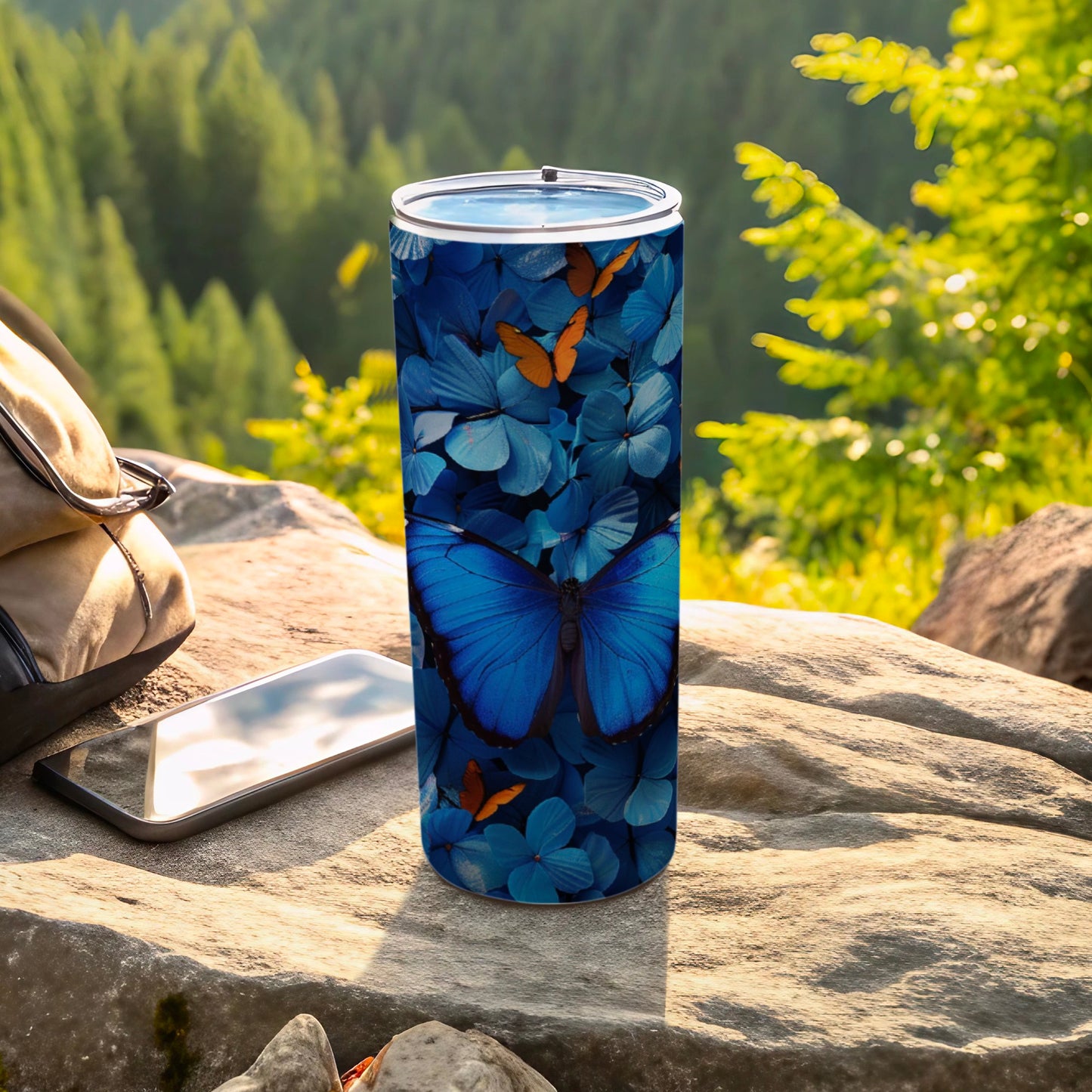 Blue morpho butterfly pattern on a tumbler, with backpack and phone nearby.