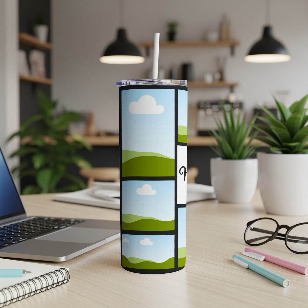 Tumbler with stacked landscape photo collage and a stylized "Q" on a light wood desk.