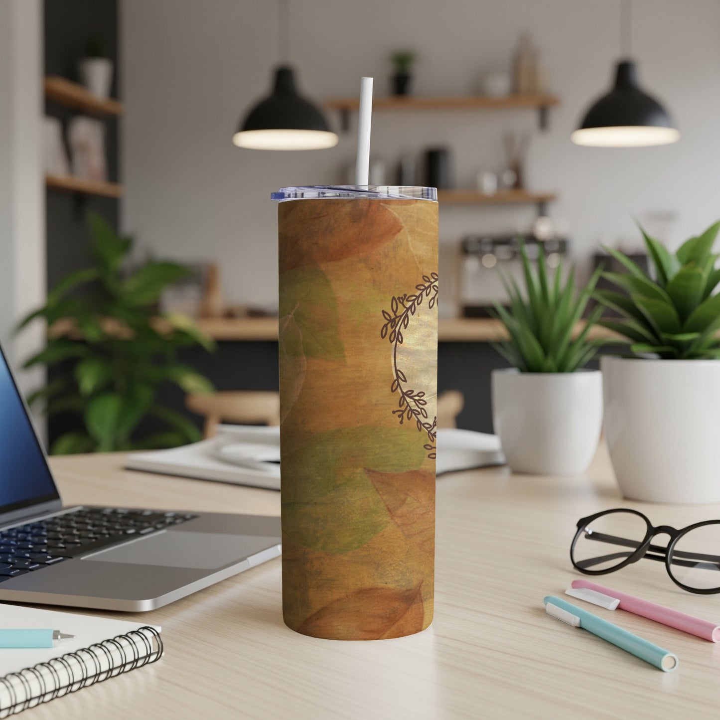 Fall leaf pattern tumbler with straw on desk.