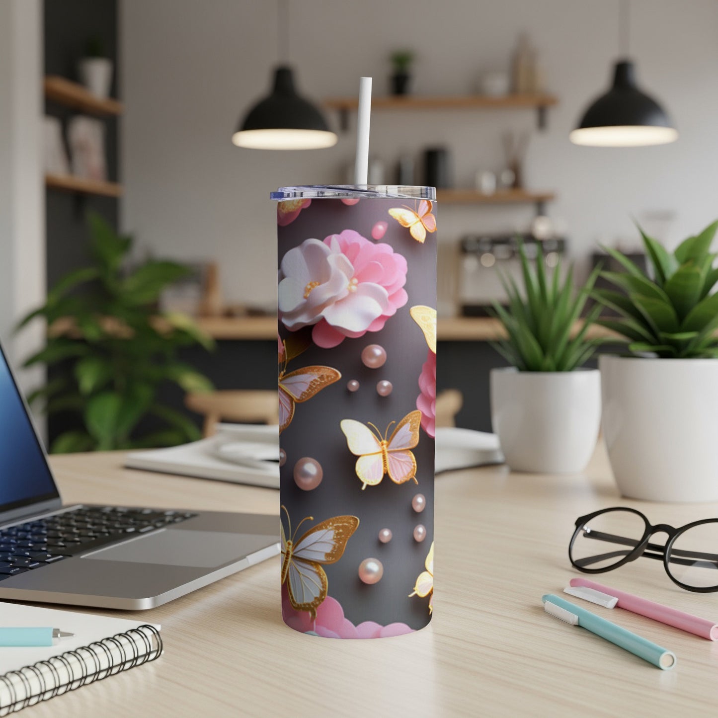 Pink and white floral butterfly tumbler with straw on a desk.