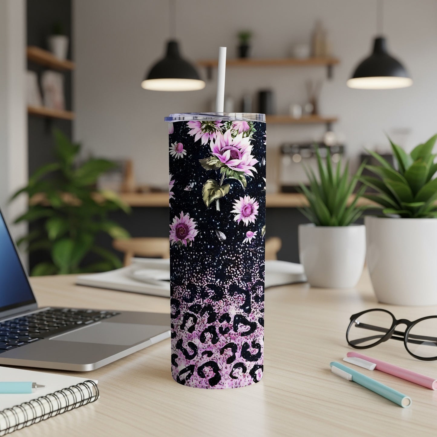 Pink leopard print and floral pattern tumbler with straw on a desk.
