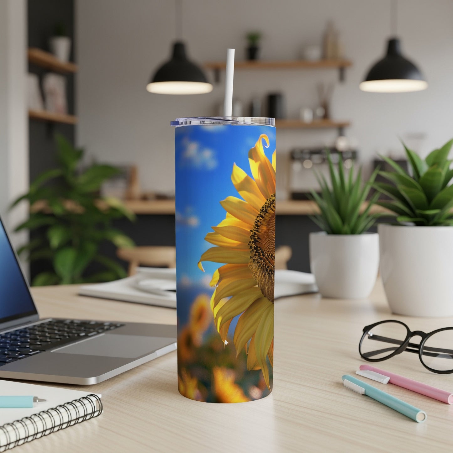 Sunflower on a skinny tumbler with a straw, on a desk.