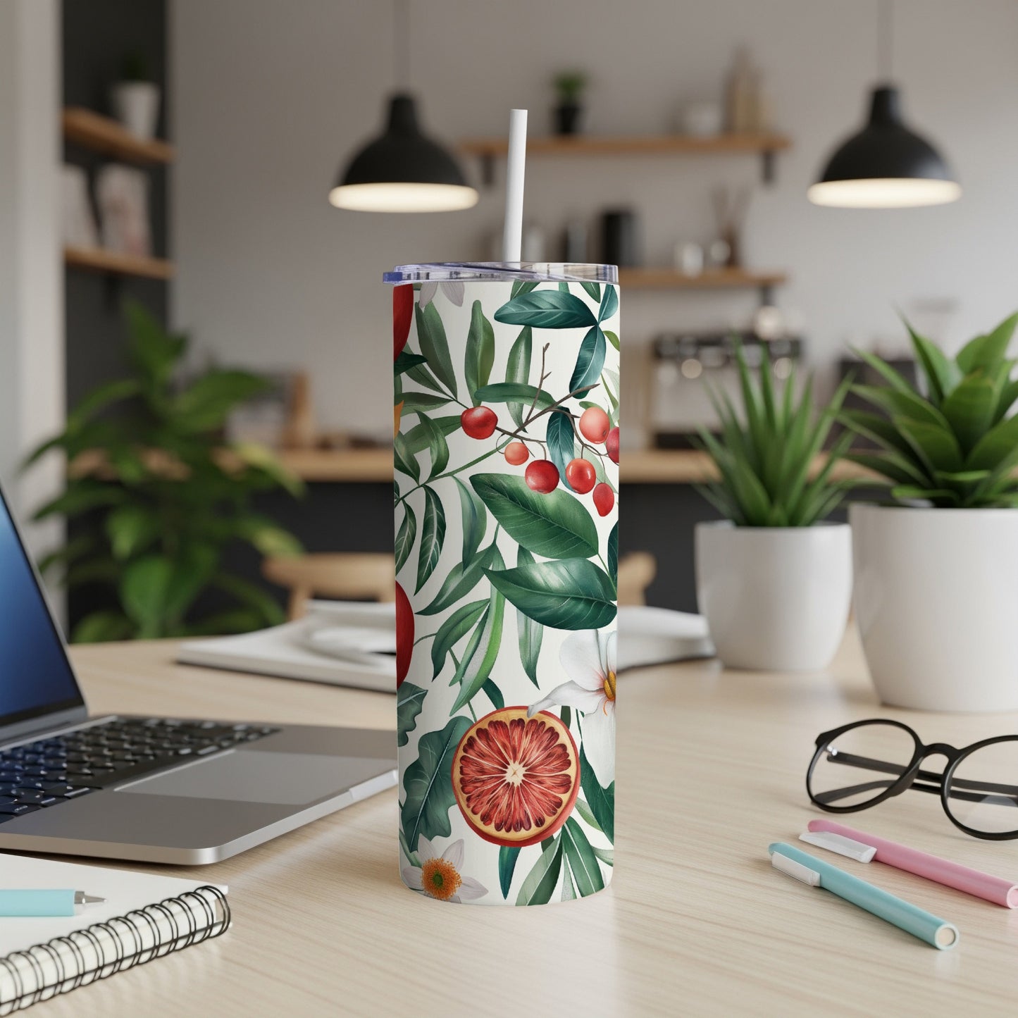 White tumbler with tropical fruit and leaf pattern and a straw.