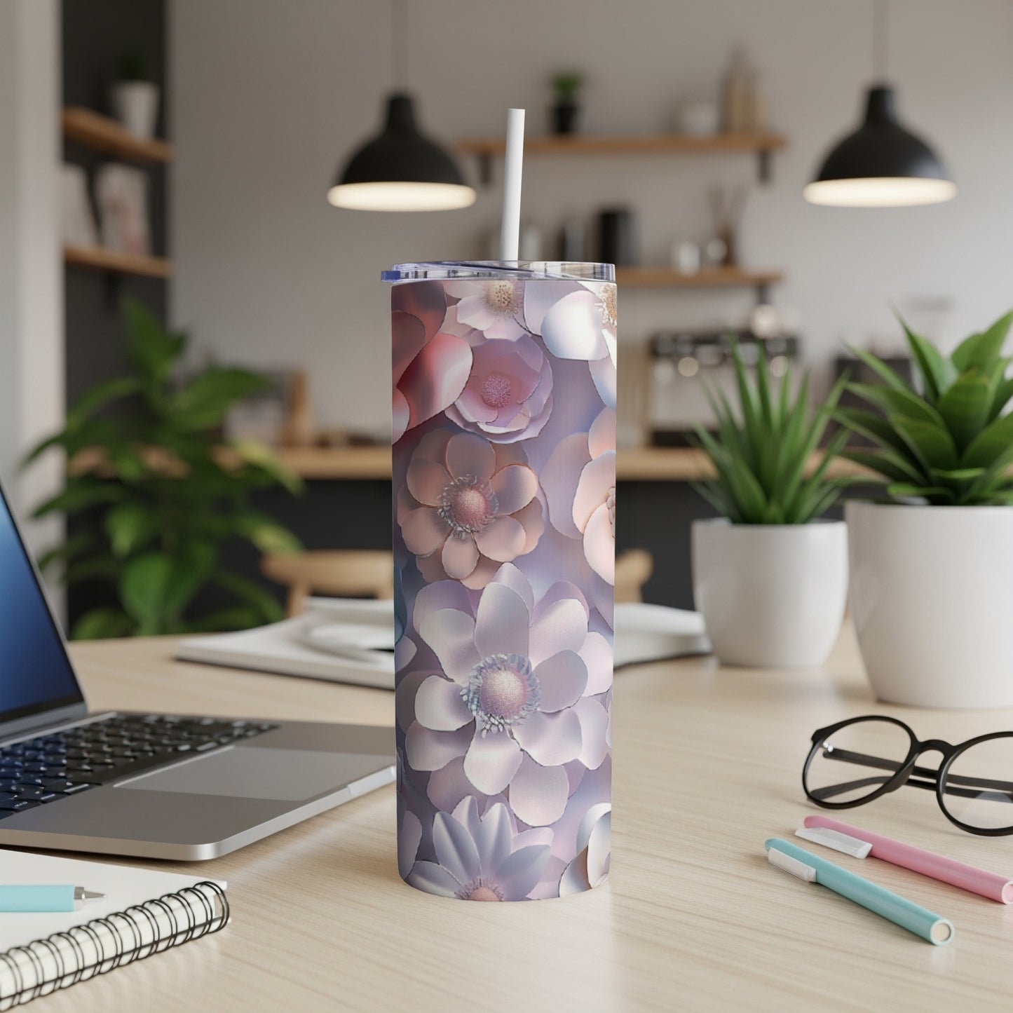 Floral pattern tumbler with straw on a desk with laptop and pens.