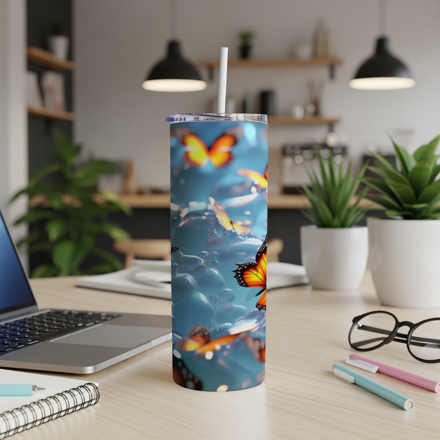 Tumbler with vibrant orange butterflies and blue bubbles on a white desk.