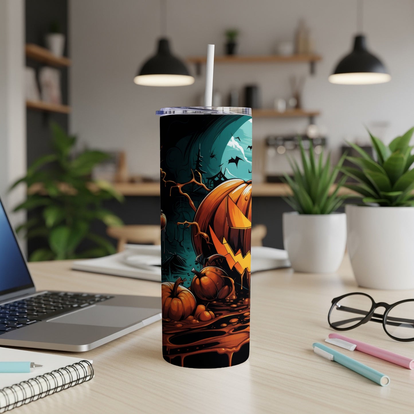 Halloween tumbler with jack-o'-lantern, pumpkins, bats, and moon on a desk.