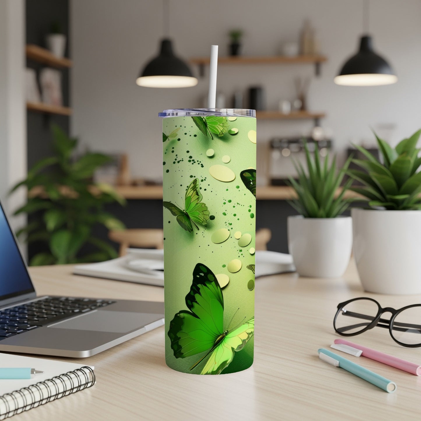 Green tumbler with butterflies and water droplets, a straw inserted.