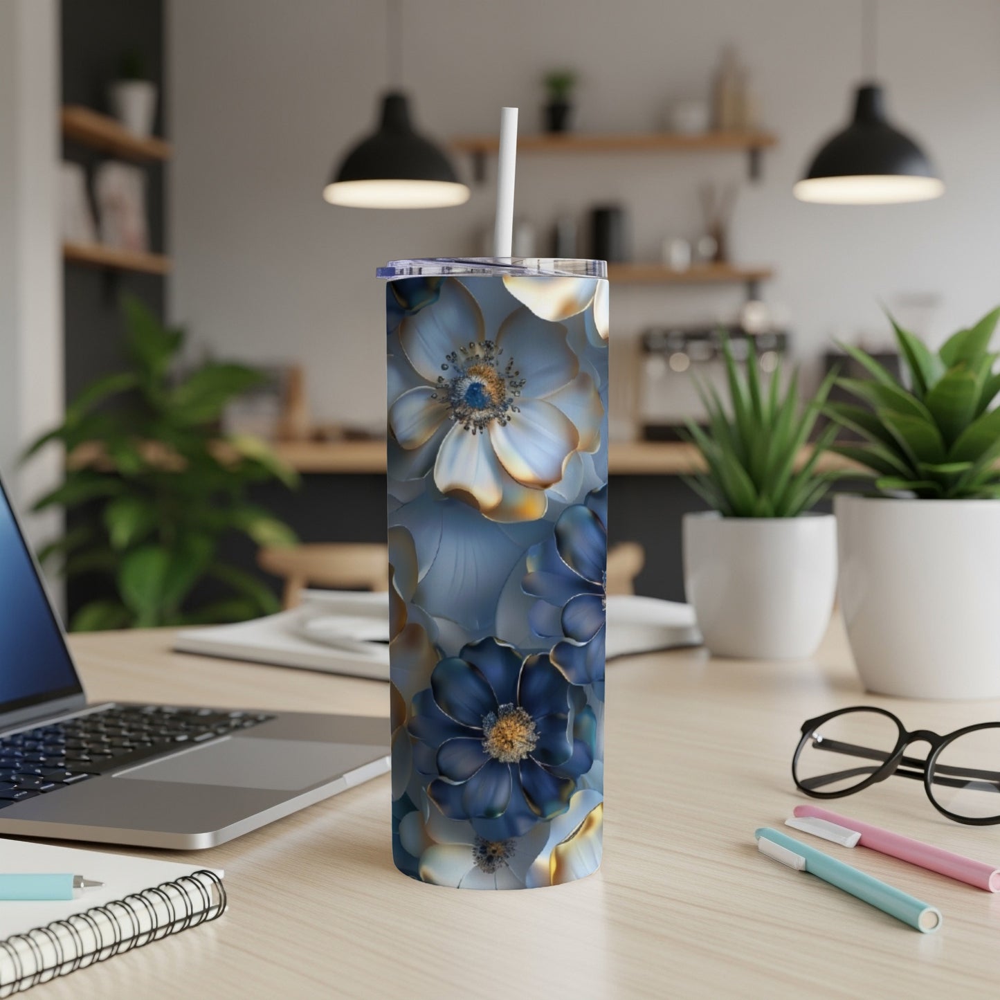 Blue floral tumbler with straw on a desk next to a laptop.