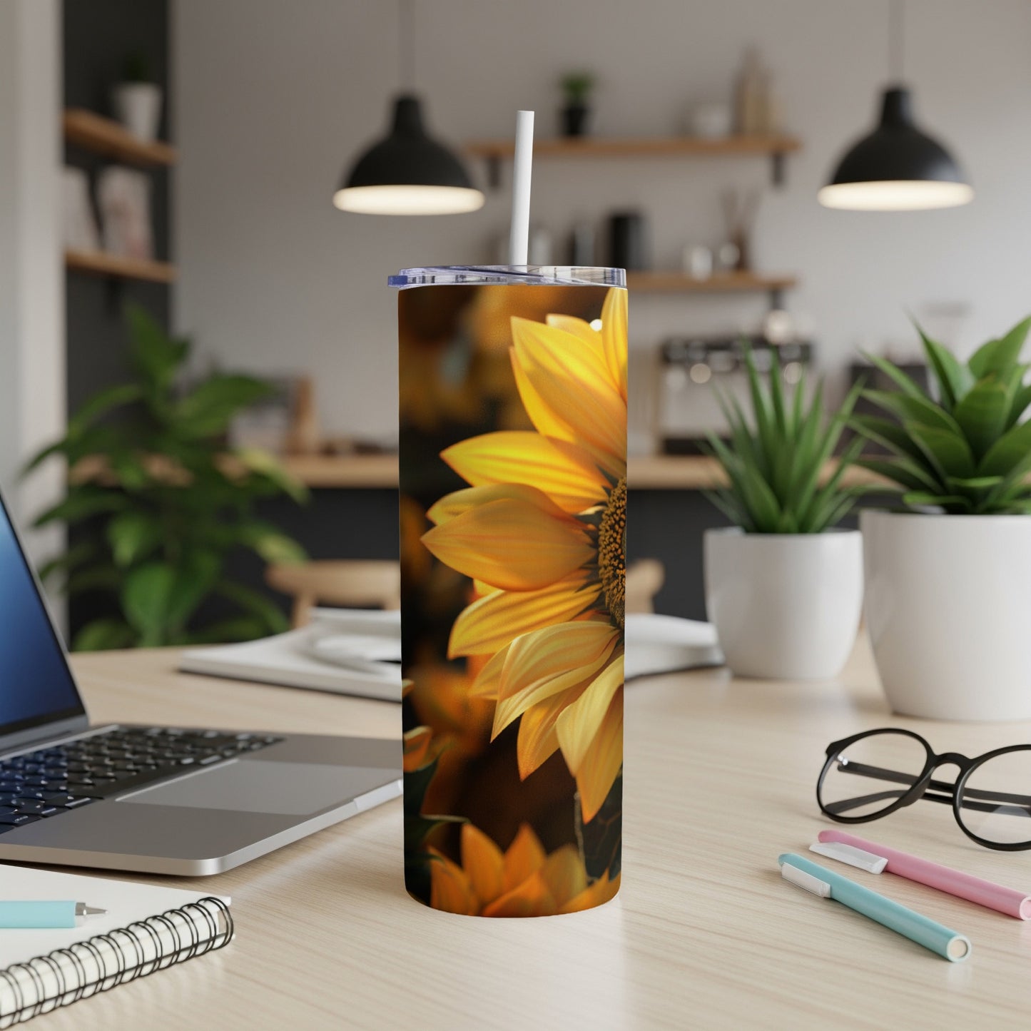 Yellow sunflower on a white tumbler with a straw on a desk.