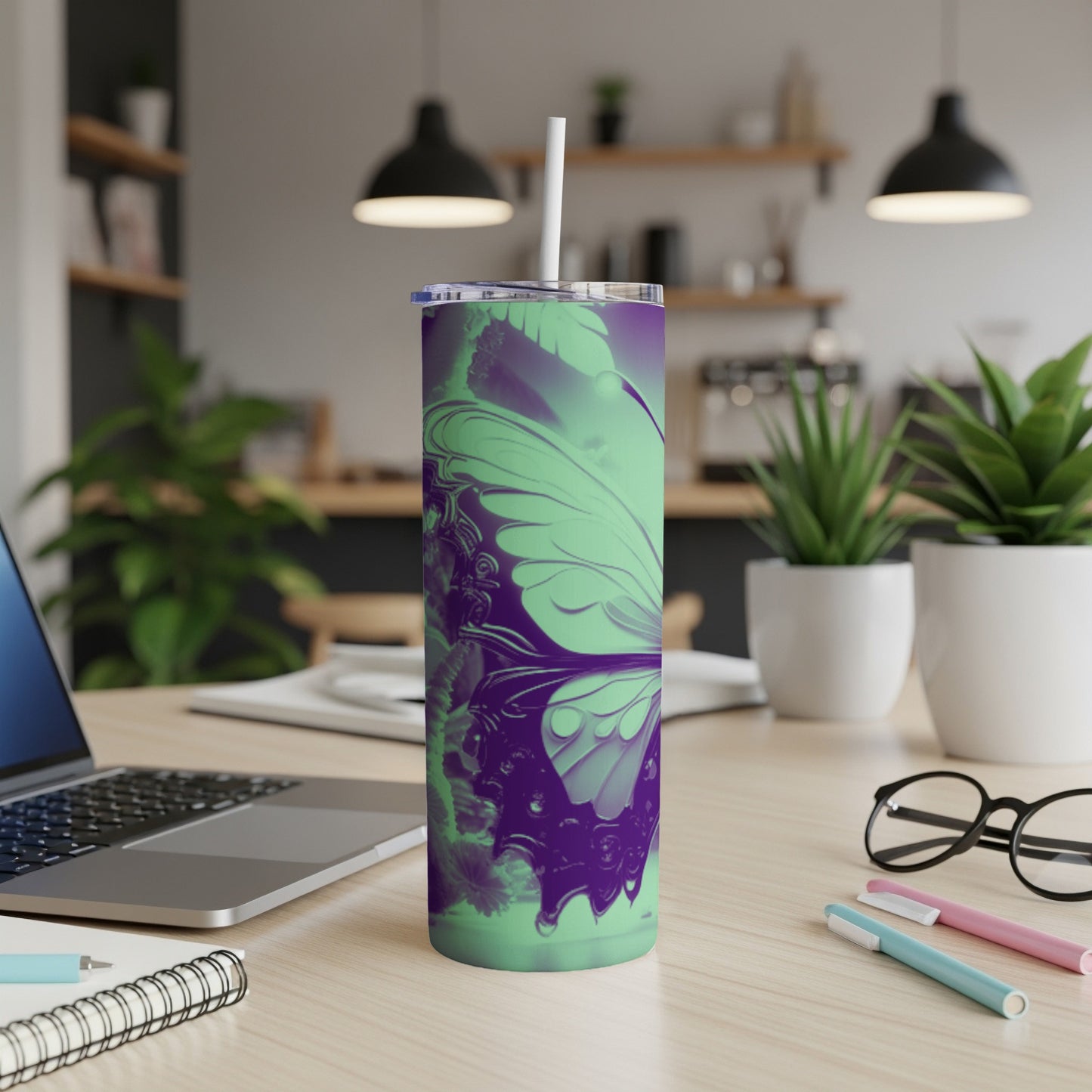 Purple and green butterfly tumbler with straw on desk.