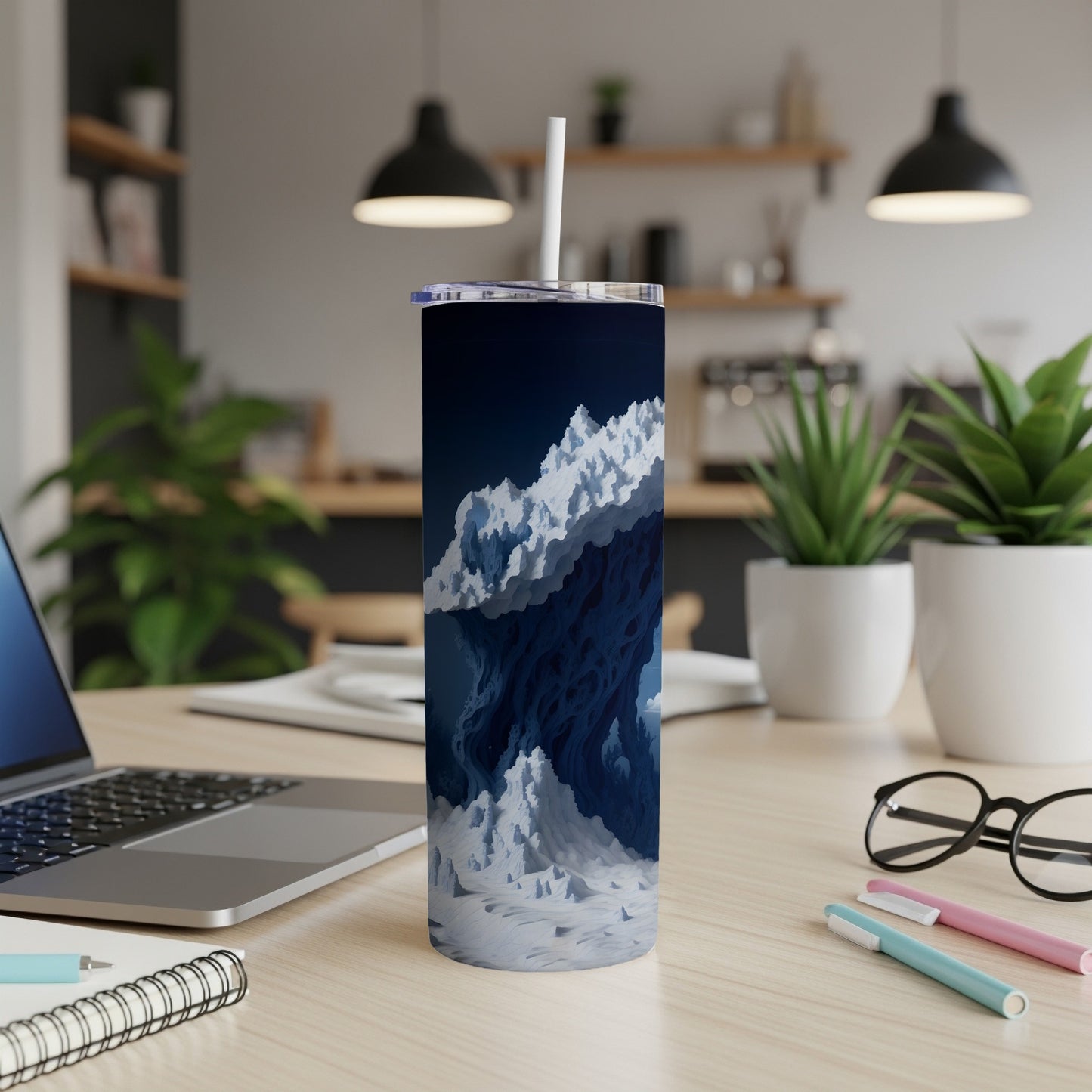 Dark blue tumbler with abstract snowy mountain range design on desk.