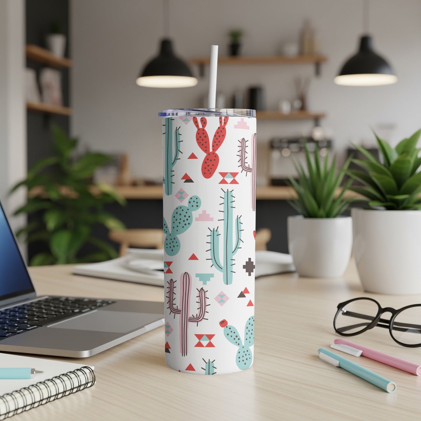 White tumbler with a pattern of colorful cartoon cacti and geometric shapes, straw inserted.