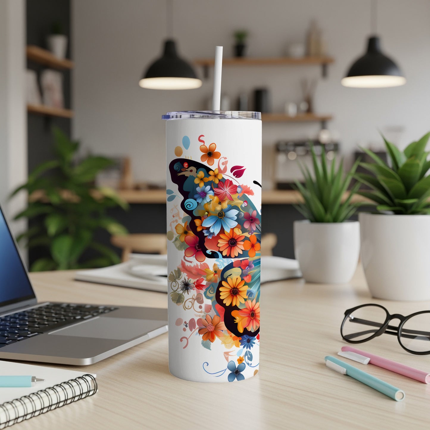 White tumbler with colorful butterfly and floral design, straw, on desk.