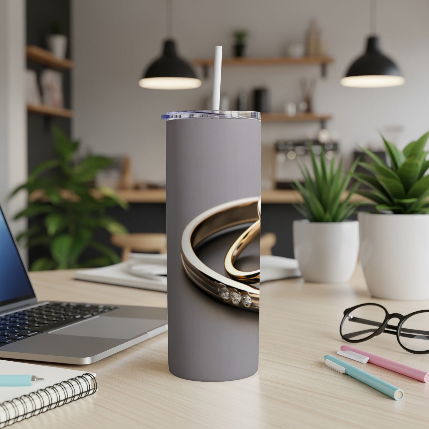 Gray tumbler with gold ring and diamond accents on a desk.
