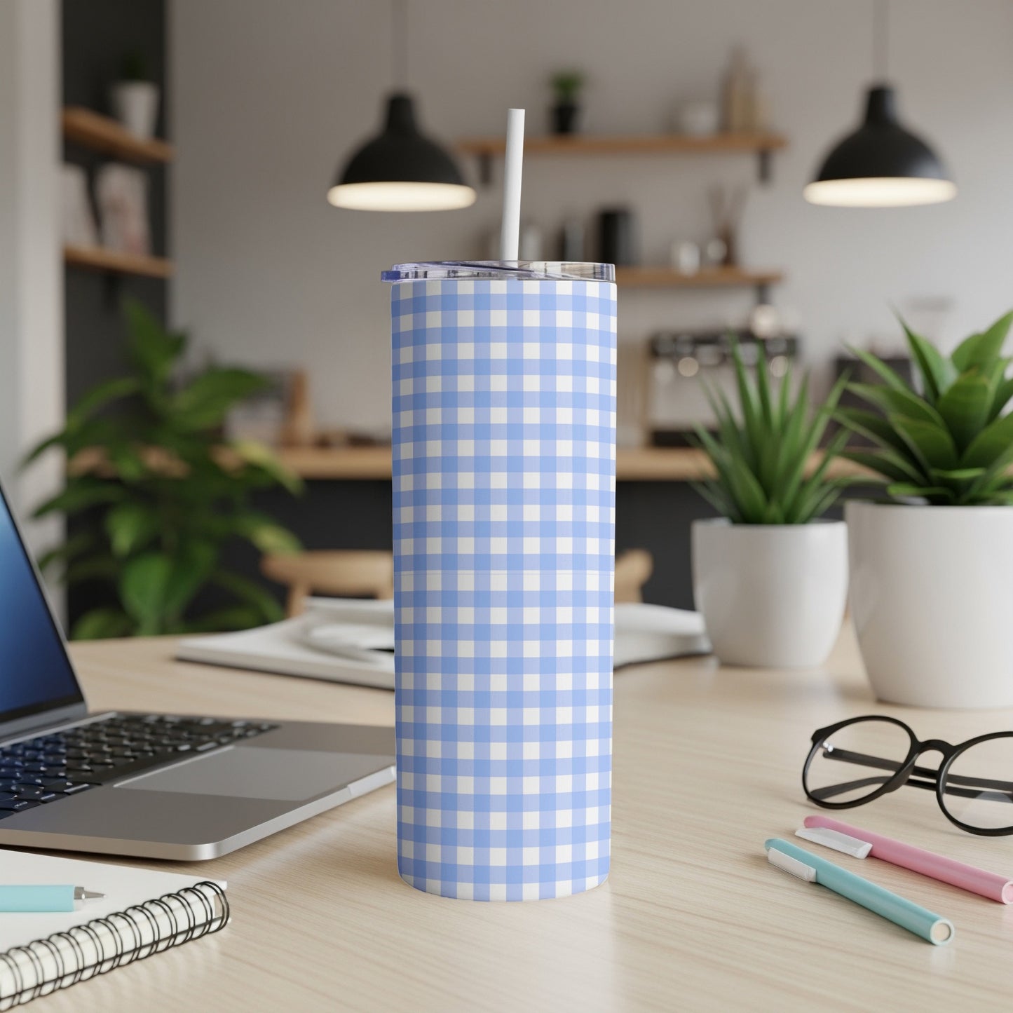 Blue and white checkered tumbler with straw on a desk.