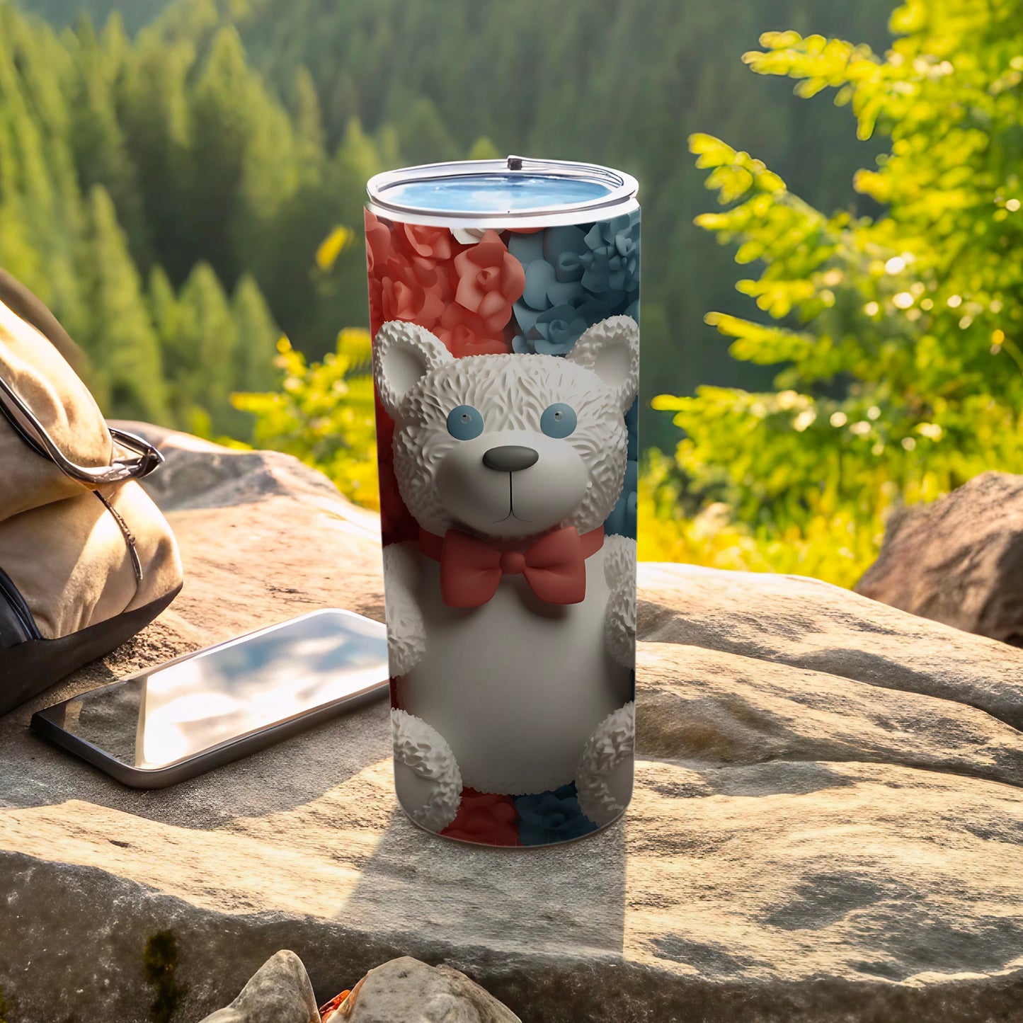 White teddy bear with bow on floral tumbler with phone and bag.