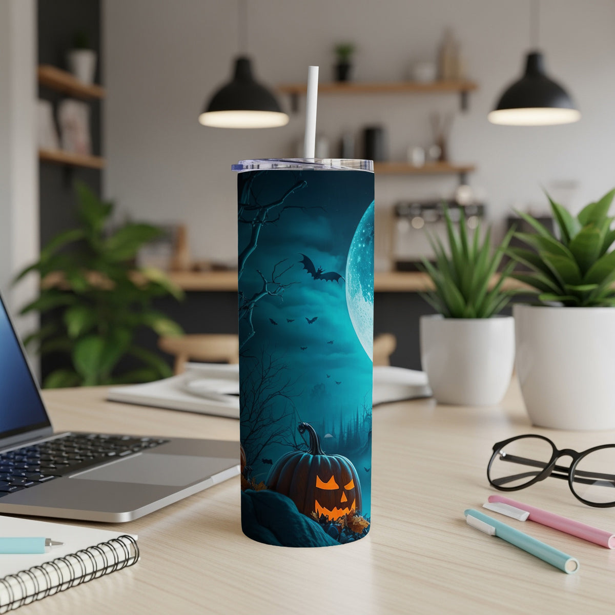 Halloween tumbler with a jack-o'-lantern, bats, and moon on a desk.