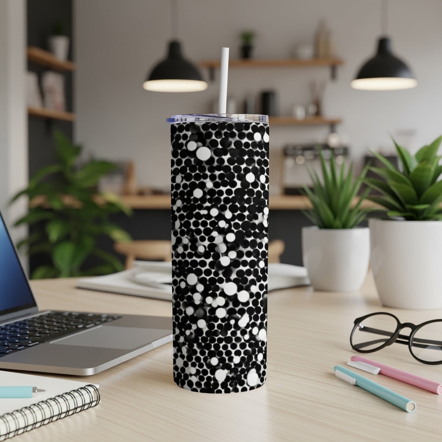 Black and white speckled tumbler with straw on a desk.